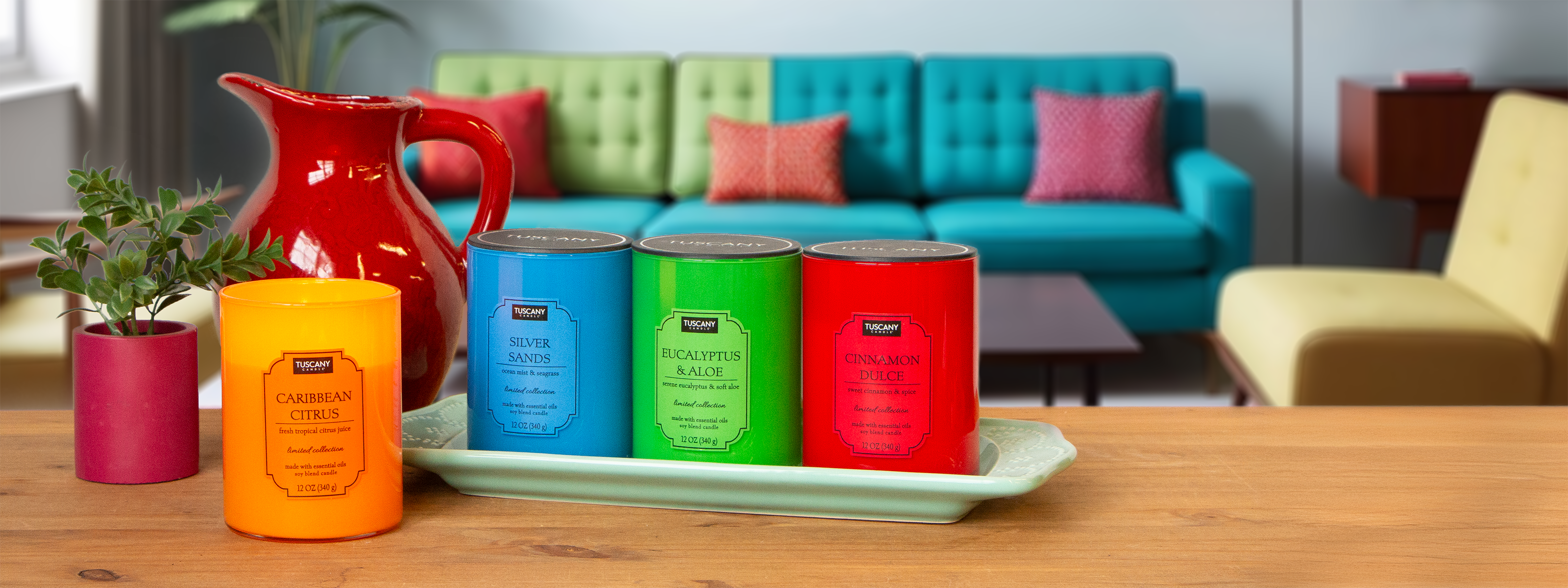 Three scented candles nestled on a blue tray; turquoise labeled "Boardwalk Stroll", orange labeled "Caribbean Citrus", green labeled "Eucalyptus". Seashells decorate the tray.