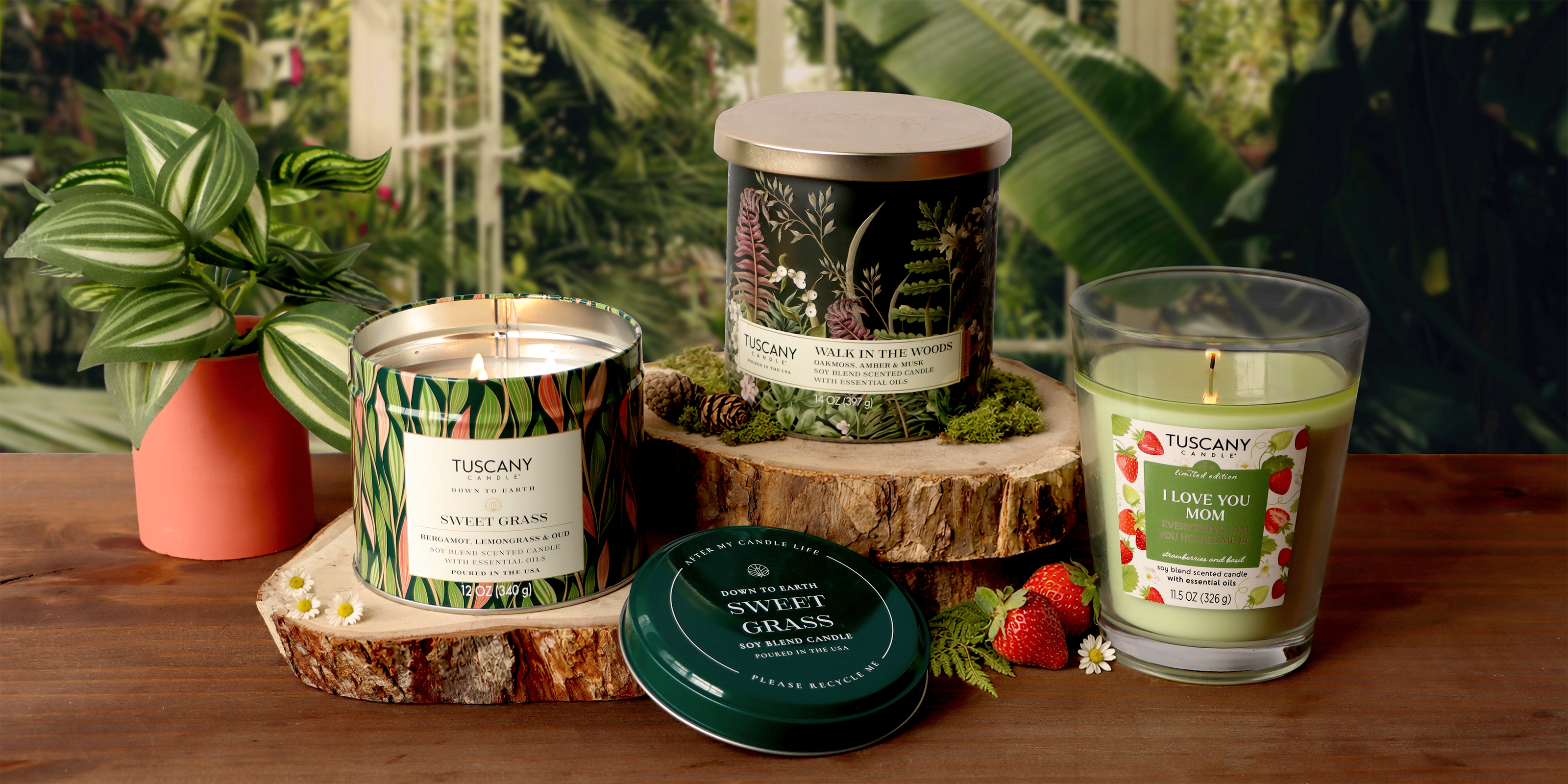 Five decorative candle jars labeled "love you MOM," "best MOM," "thank you MOM," "sweet MOM," and "amazing MOM," with floral designs on a wooden surface, surrounded by flowers.