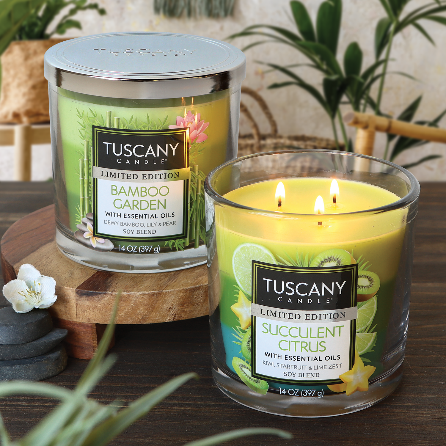 Two Tuscany Candle® SEASONAL Succulent Citrus Long-Lasting Scented Jar Candles (14 oz), one labeled "succulent citrus" and the other "bamboo garden," displayed with lit wicks on a wooden surface, surrounded by natural decor elements.