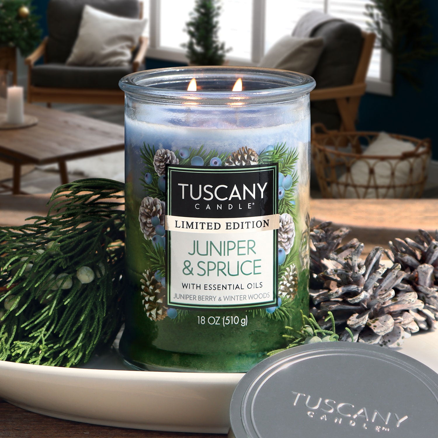 18oz 'Juniper & Spruce' scented candle by Tuscany Candle in a glass jar, showcasing its tri-color layers, reminiscent of sparkling juniper berry, frosty winter woods, and aromatic rosemary.