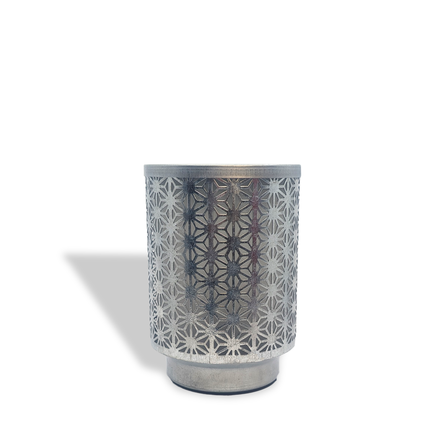 The Tuscany Candle® Everyday Galvanized Metal Outlet Wax Melt Warmer features an intricate geometric flower pattern casting a shadow on a white background.