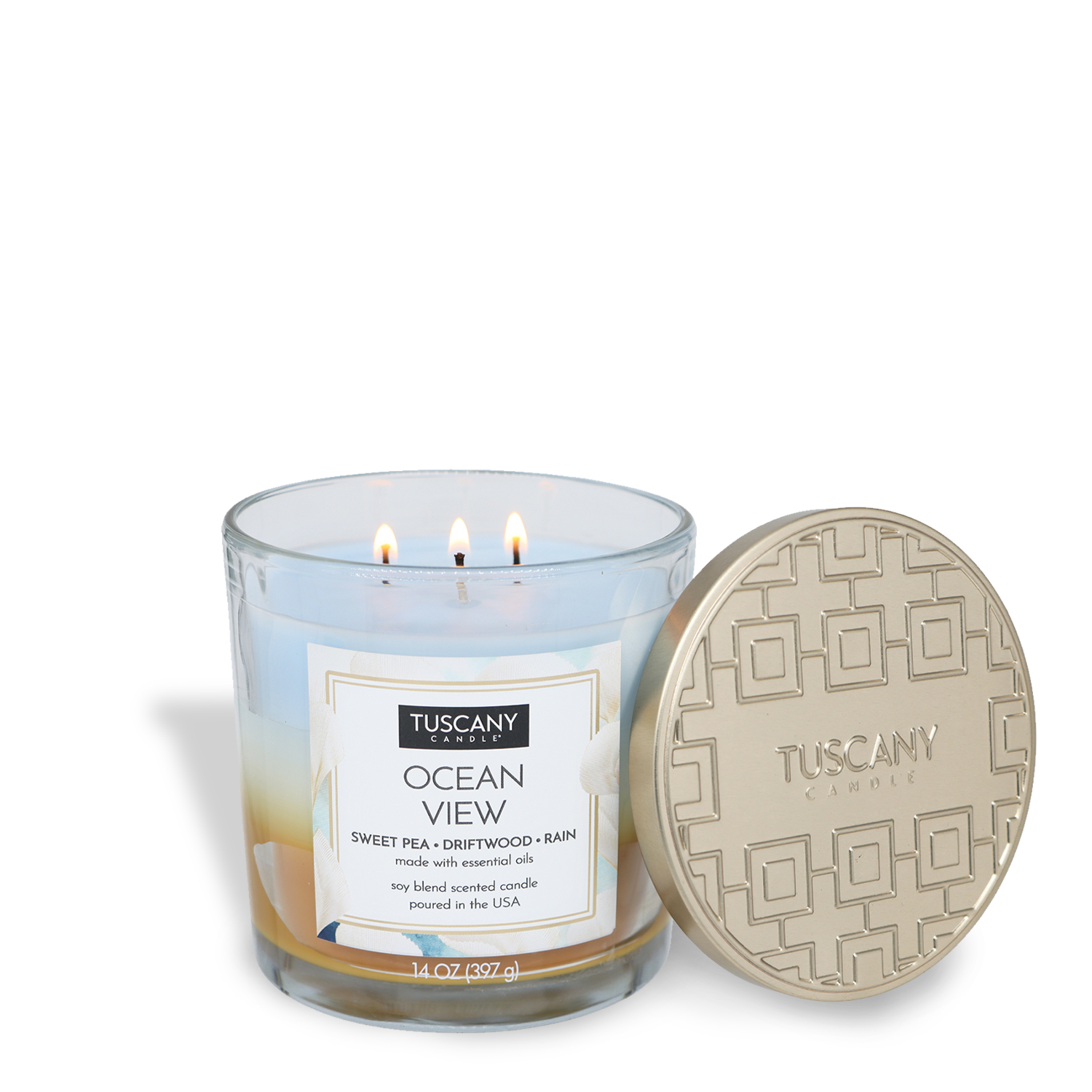 A Tuscany Candle® EVD Ocean View Long-Lasting Scented Jar Candle (14 oz) with three lit wicks sits by its gold-patterned lid. Enjoy driftwood, sweet pea, and rain notes in this beautifully designed candle.