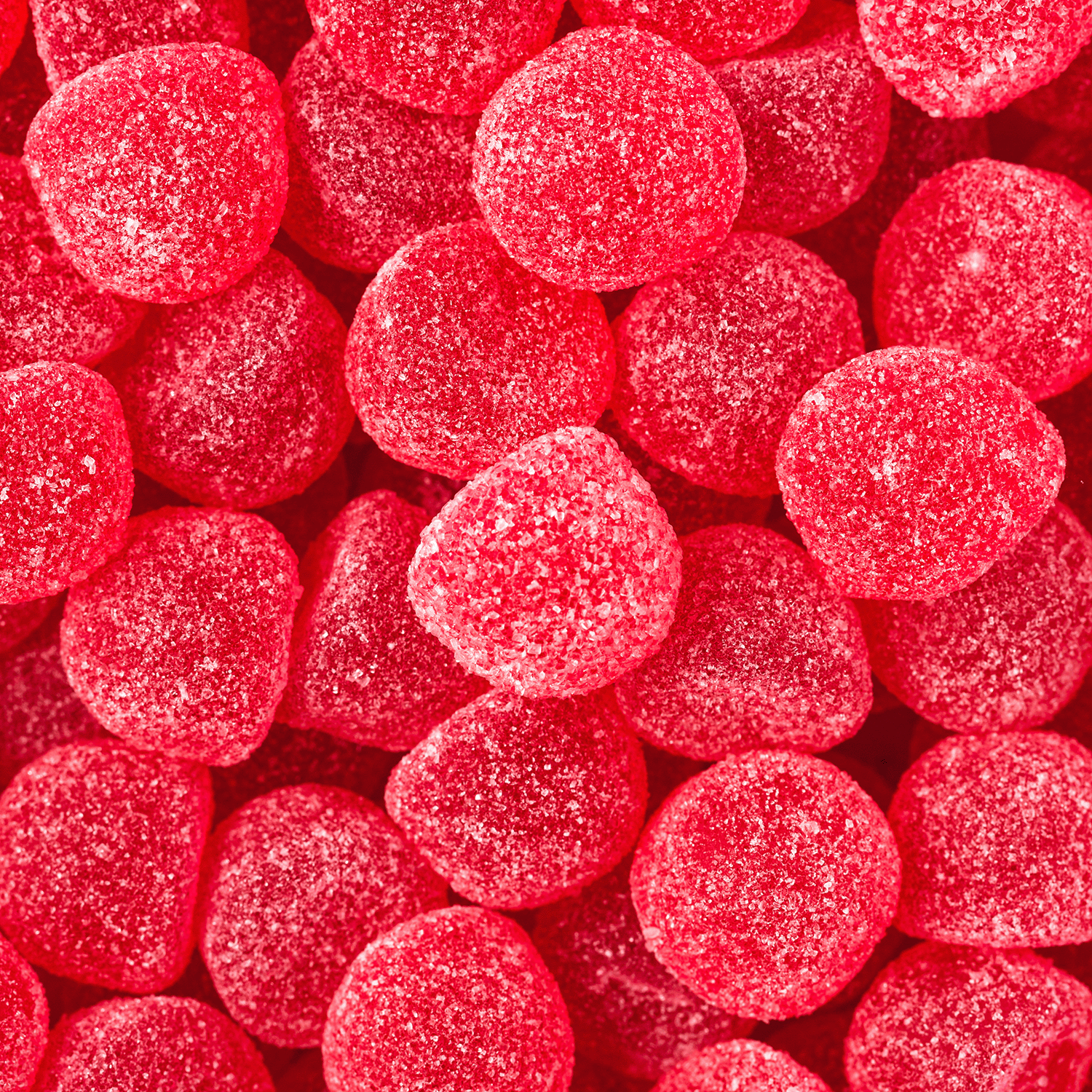 A close-up of red, round, sugar-coated gummies evokes the sweet watermelon scent of Tuscany Candle® SEASONAL’s Melon Berry Bellini: Watermelon Scented Summer Candle (12 oz) from the Island Glam Collection.