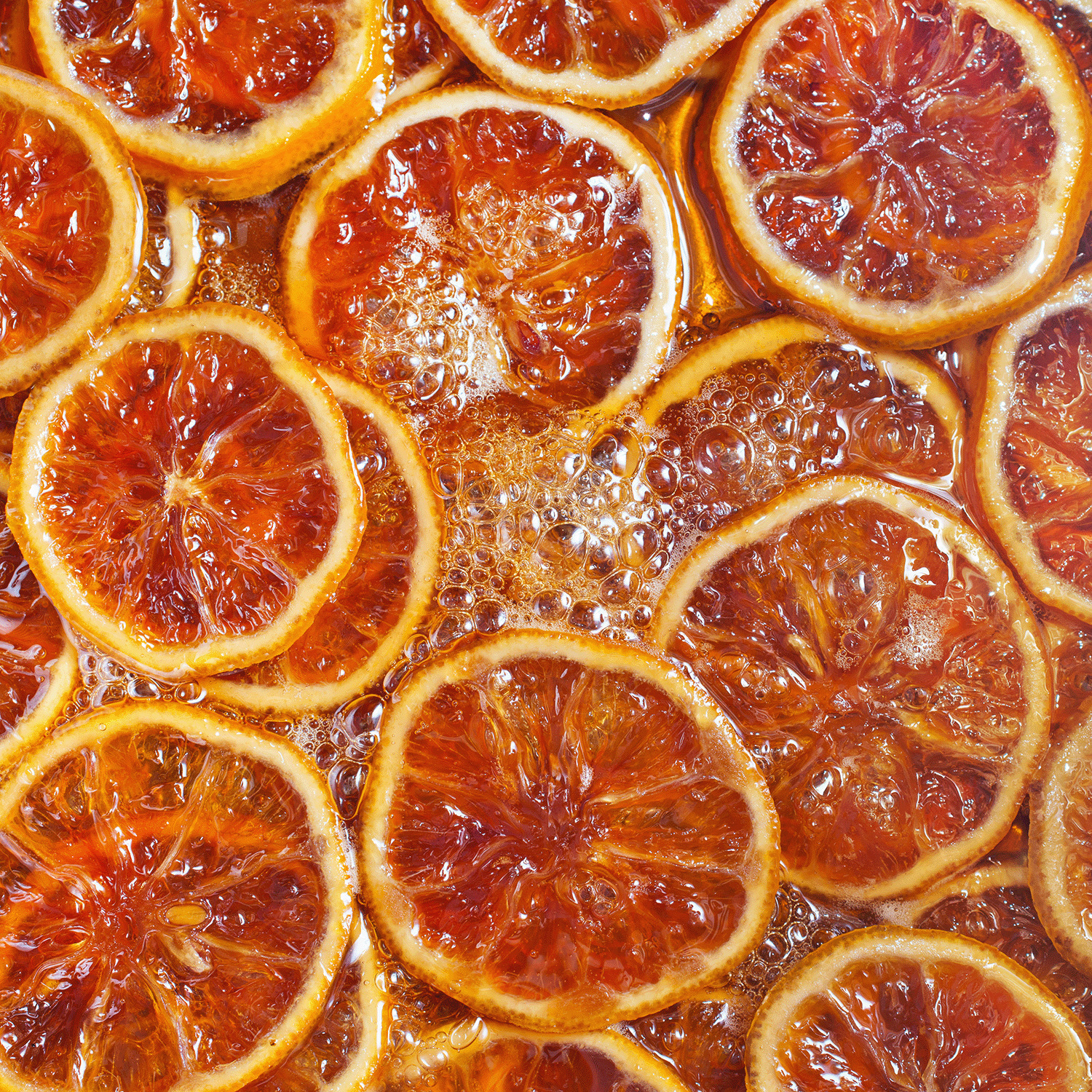 Close-up of Bourbon Caramel Spice: Maple Sugar & Cinnamon Scented Fall Candle by Tuscany Candle® SEASONAL, its warm, glazed glow evoking orange slices caramelizing in syrup. 12 oz, Bakery Tins Collection.