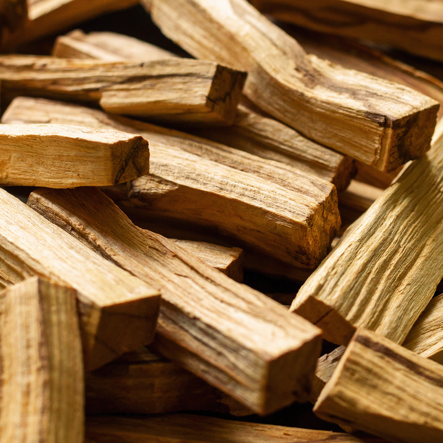 A close-up of stacked, rough-cut wood evokes the earthy aroma of Tuscany Candle® SEASONAL’s Enchanted Oakmoss: Smoky Incense & Creeping Oakmoss Scented Halloween Candle (12 oz) from the Spooky Skull Collection.