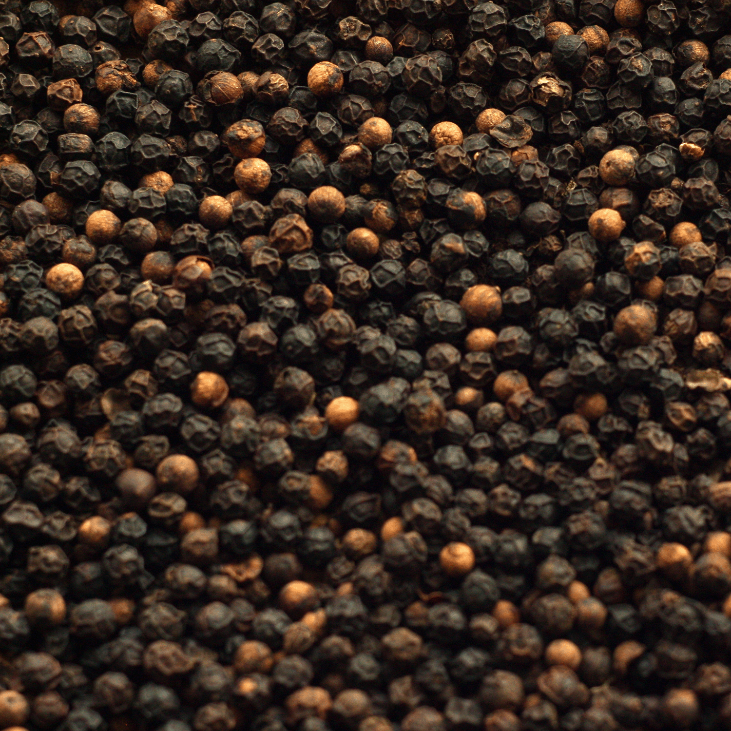 Close-up of whole black peppercorns, highlighting their round, textured look—evocative of the bold aroma found in Tuscany Candle® SEASONAL Christmas Cabin: Smoky Suede & Birch Scented Holiday Candle (18 oz).