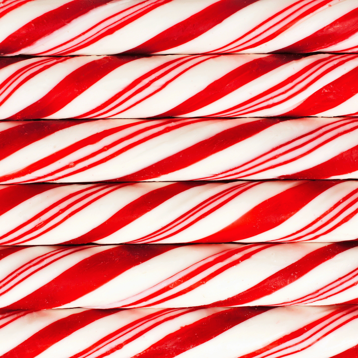 Close-up of stacked red and white striped candy canes evokes the festive aroma of Tuscany Candle® SEASONAL Candy Cane Forest: Peppermint & Balsam Scented Holiday Wax Melt (2.5 oz), a seasonal treat for your home.