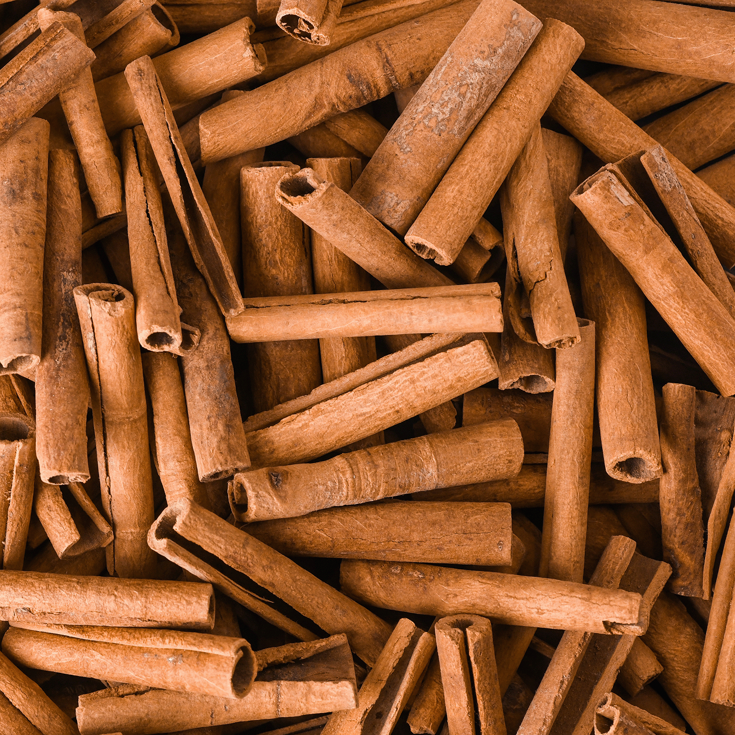 A close-up of cinnamon sticks highlights their rich texture, perfect for the Cinnamon Pinecones: Warm Cinnamon & Clove Scented Holiday Candle (14 oz) from Tuscany Candle® SEASONAL’s Traditions Collection—ideal for festive aromas.