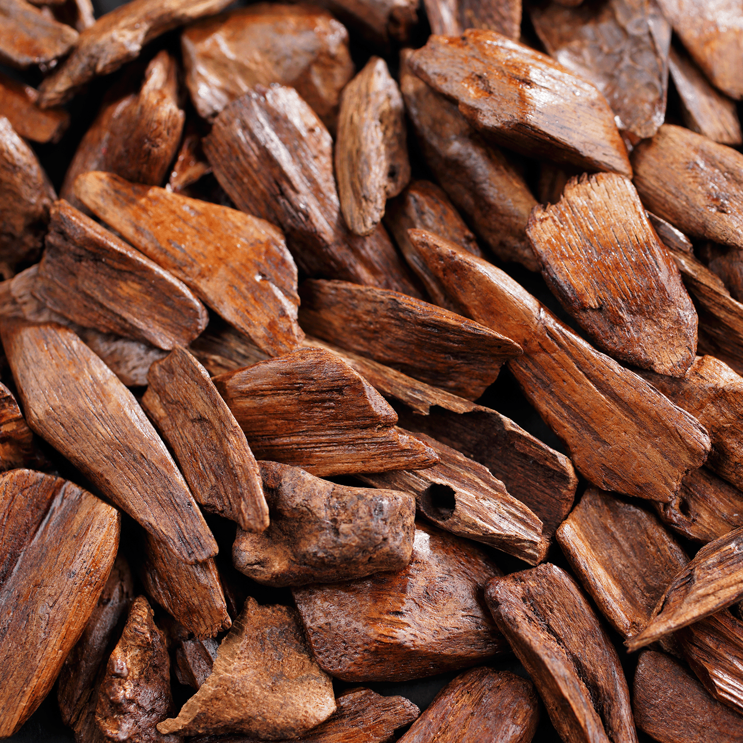 Close-up of brown wooden chips with rough textures—ideal accents for crafting Tuscany Candle® SEASONAL’s Peace: Warm Vanilla & Cardamom Scented Holiday Wooden Wick Candle (13 oz).