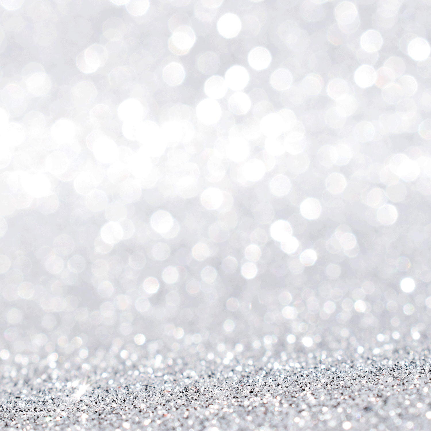 A close-up of silver glitter and bright bokeh lights evokes the festive aroma of Tuscany Candle® SEASONAL Jolly: Spicy Clove & Frosted Spruce Scented Holiday Wooden Wick Candle (13 oz).