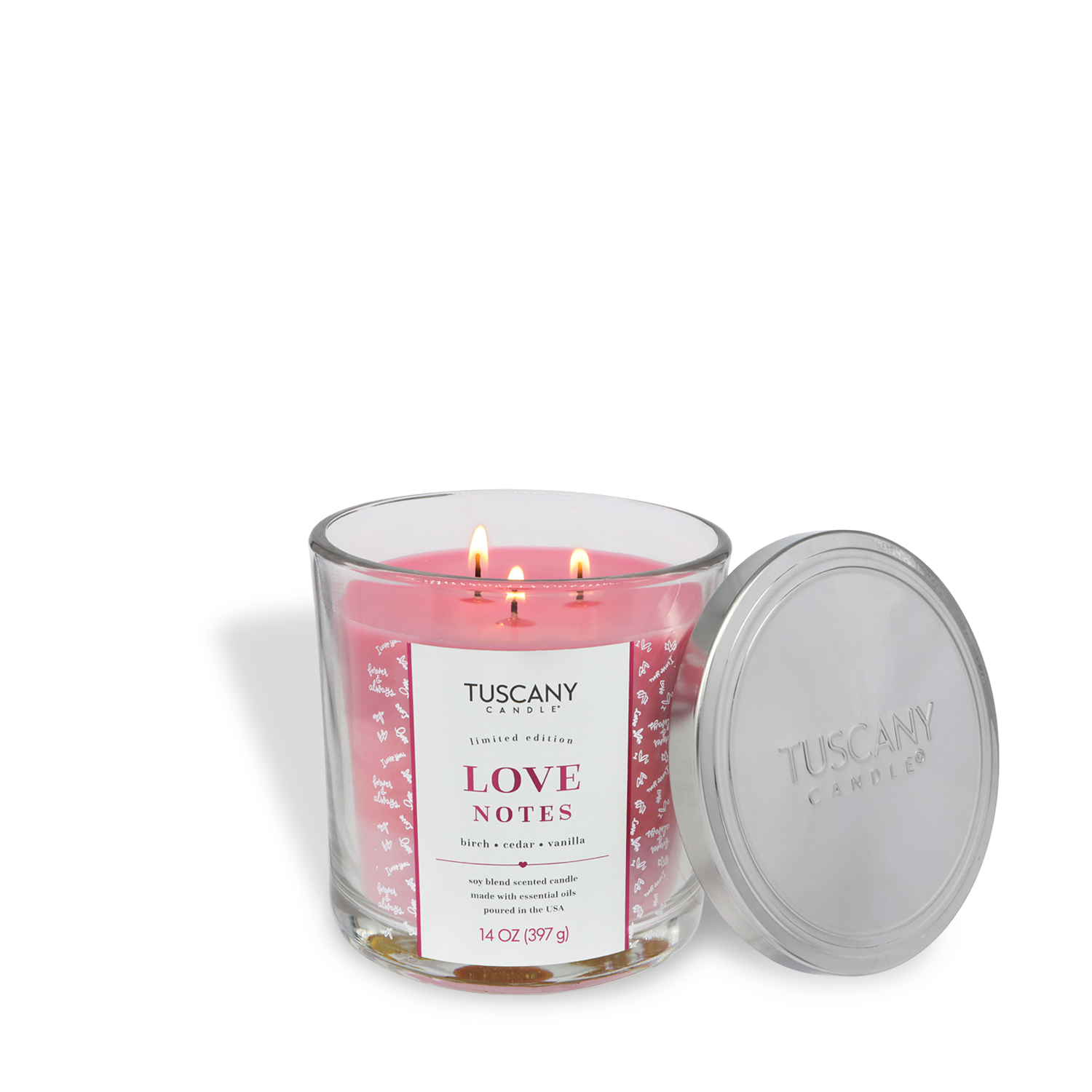 A Tuscany Candle® SEASONAL "Love Notes: Birch & Cedarwood Scented Valentine's Candle" (14 oz) with three lit wicks in a glass jar and its silver lid open beside it.