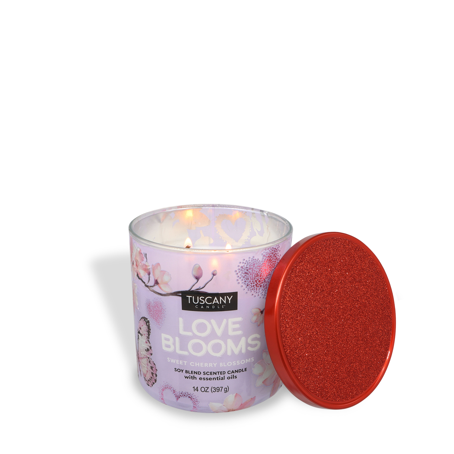 A lit Tuscany Candle® SEASONAL "Love Blooms: Cherry Blossom Scented Valentine's Candle" (14 oz) is shown with its red glittery lid resting beside it.