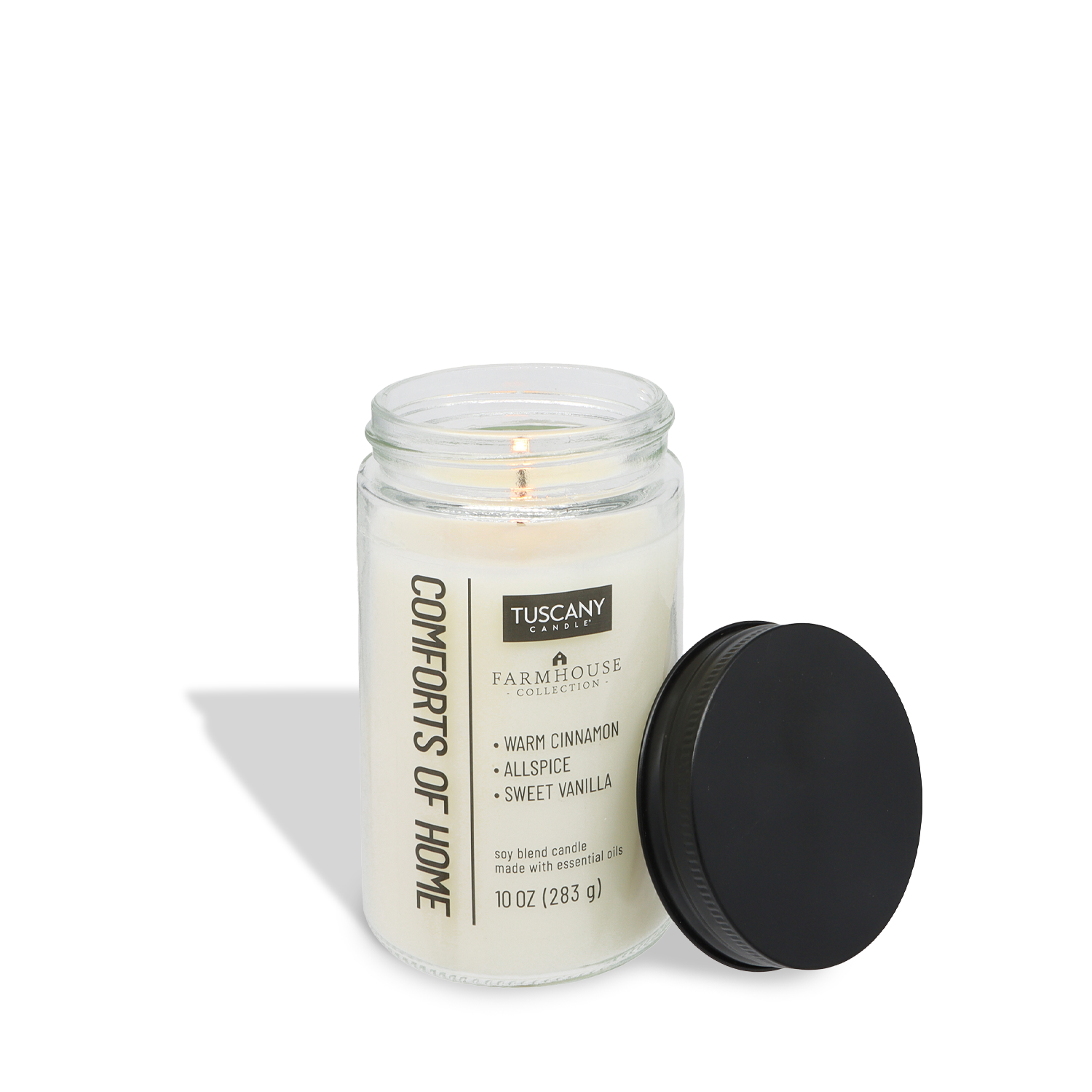A lit Tuscany Candle® EVD Comforts of Home Scented Jar Candle (10 oz) from the Farmhouse Collection, featuring cinnamon vanilla fragrance, sits in a mason jar with a black lid beside it.