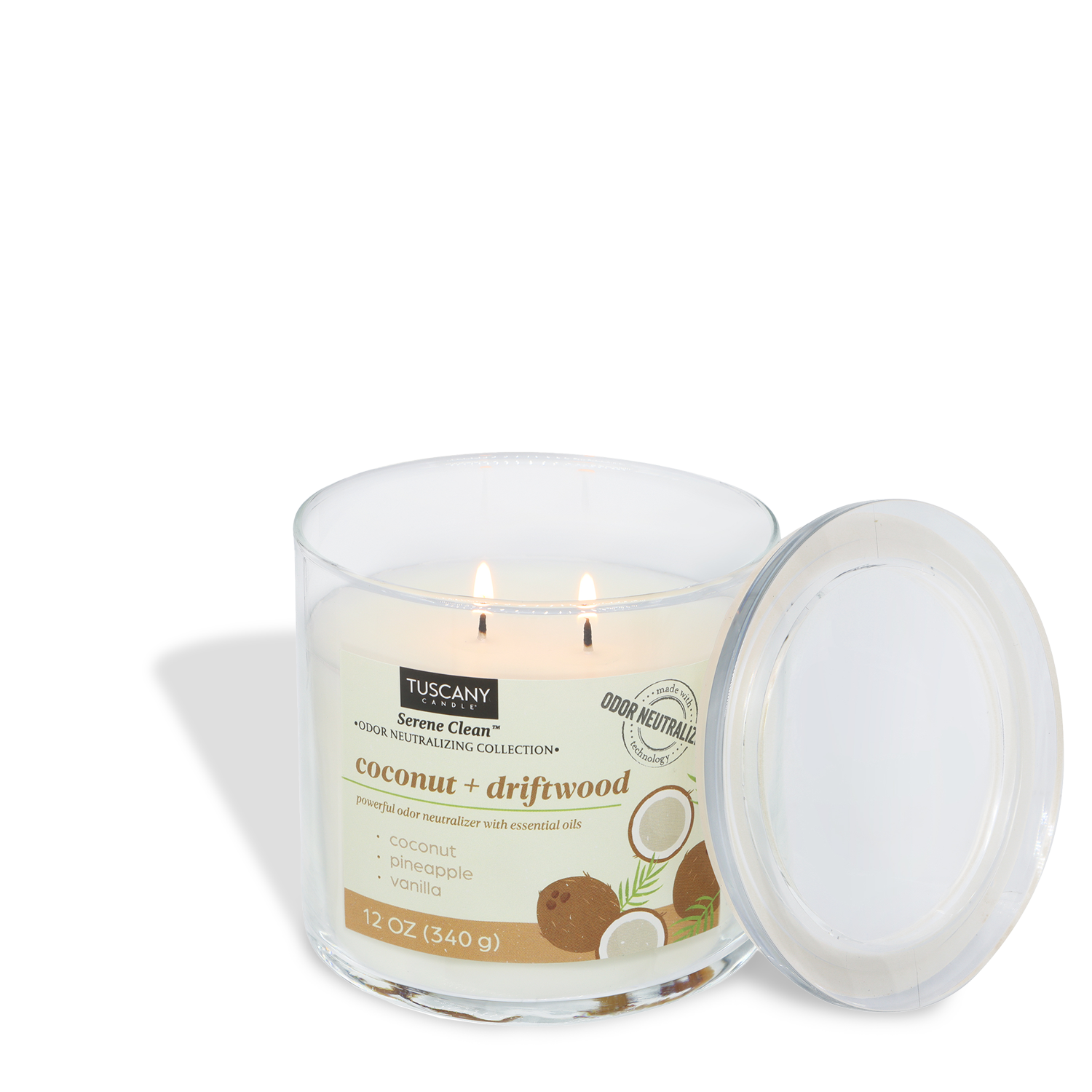 A lit Tuscany Candle® Everyday Coconut + Driftwood Scented Odor Neutralizing Candle (12 oz) from the Serene Clean Collection sits in a clear glass jar with the lid aside, featuring coconut, pineapple, and vanilla artwork hinting at its tropical aroma.