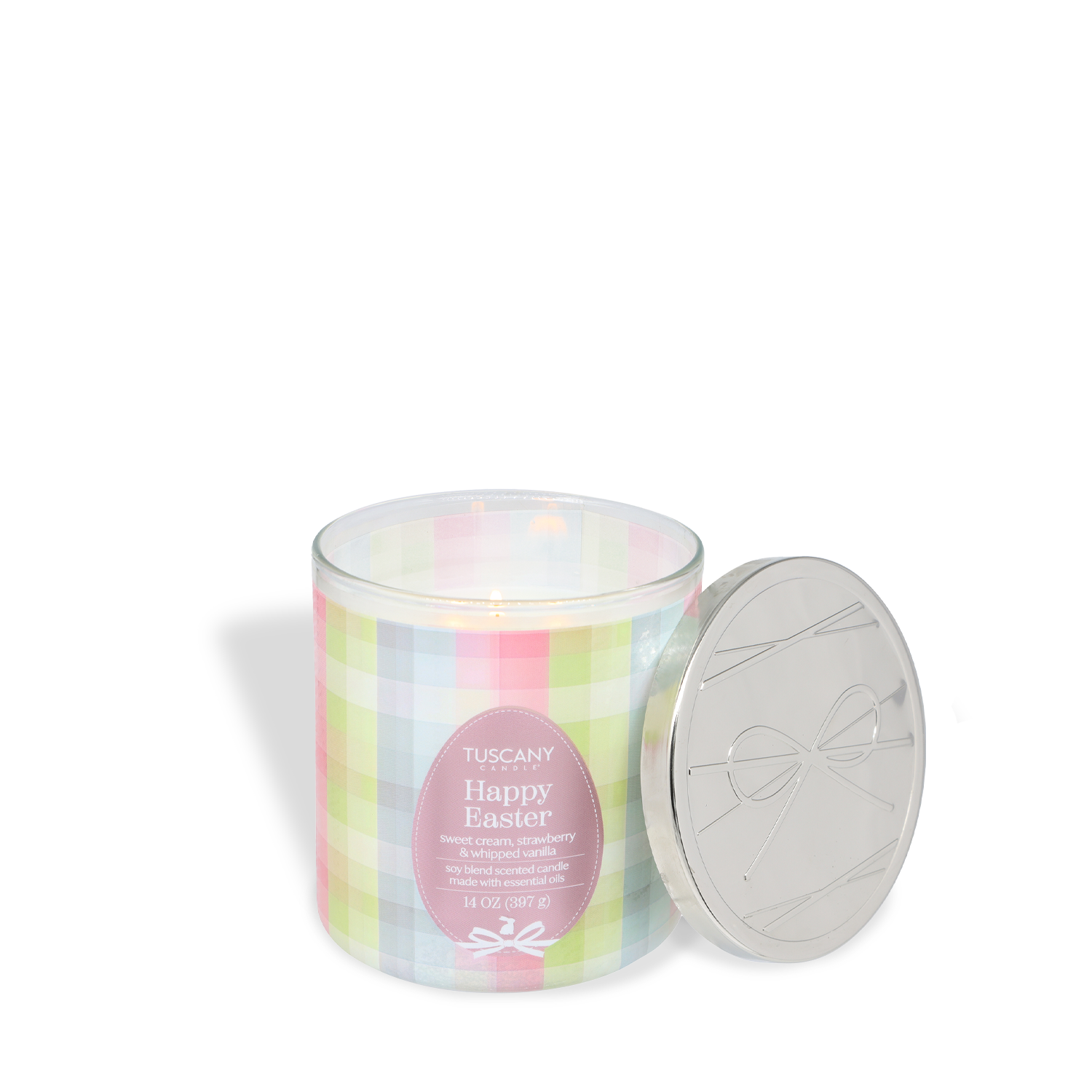 A lit Tuscany Candle® "Happy Easter: Strawberries & Cream Scented Spring Candle" (14 oz) in a pastel plaid glass jar, with a silver lid placed beside it.