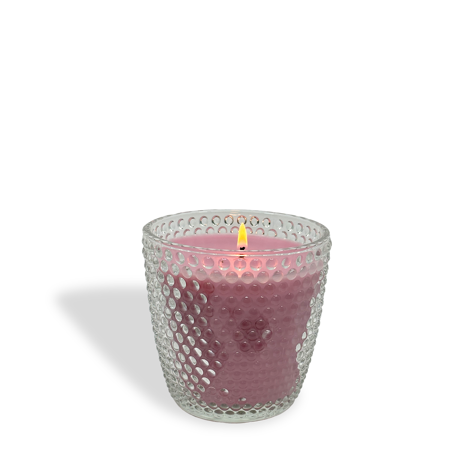 A lit Tuscany Candle® Berry Basket: Strawberry & Watermelon Scented Easter Candle (8.5 oz) glows in a textured clear glass holder, its flame and shadow visible against a white background.