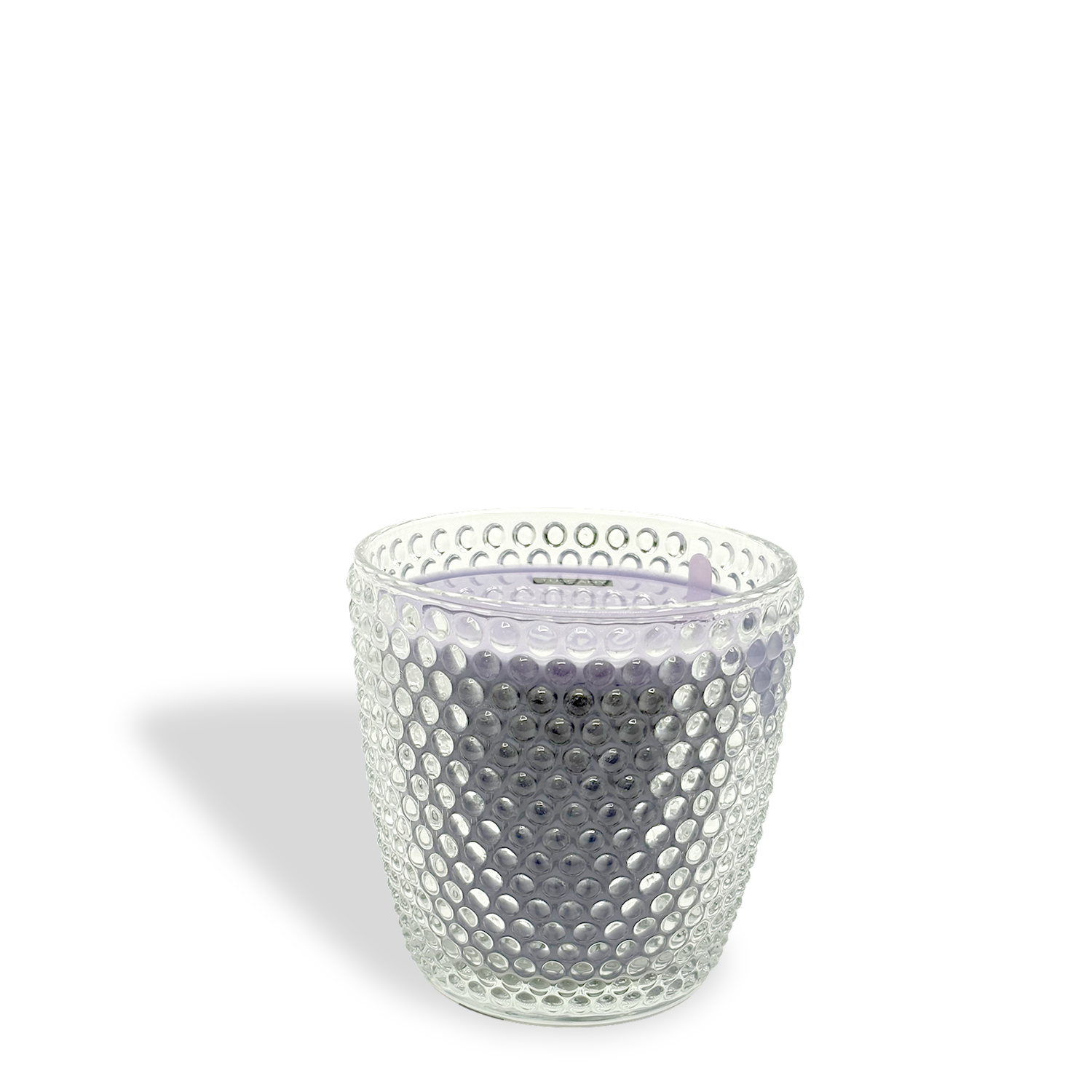 A textured clear glass container holds Tuscany Candle®’s Lavender Lollipops: Grape & Jasmine Scented Easter Candle (8.5 oz), a light purple single-wick candle.