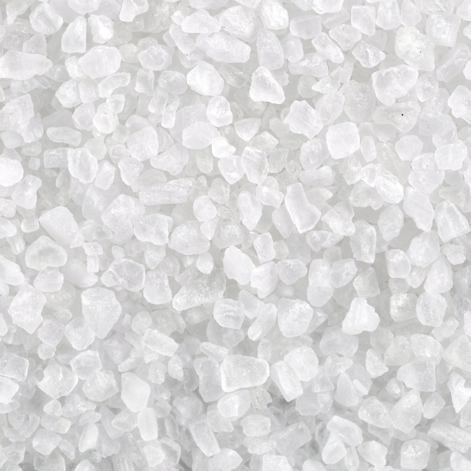 Close-up of coarse white salt crystals, reminiscent of the fresh scent of Tuscany Candle® SEASONAL Sea Salt & Minerals: Mossy Kelp & Driftwood Scented Spring Candle (18 oz).