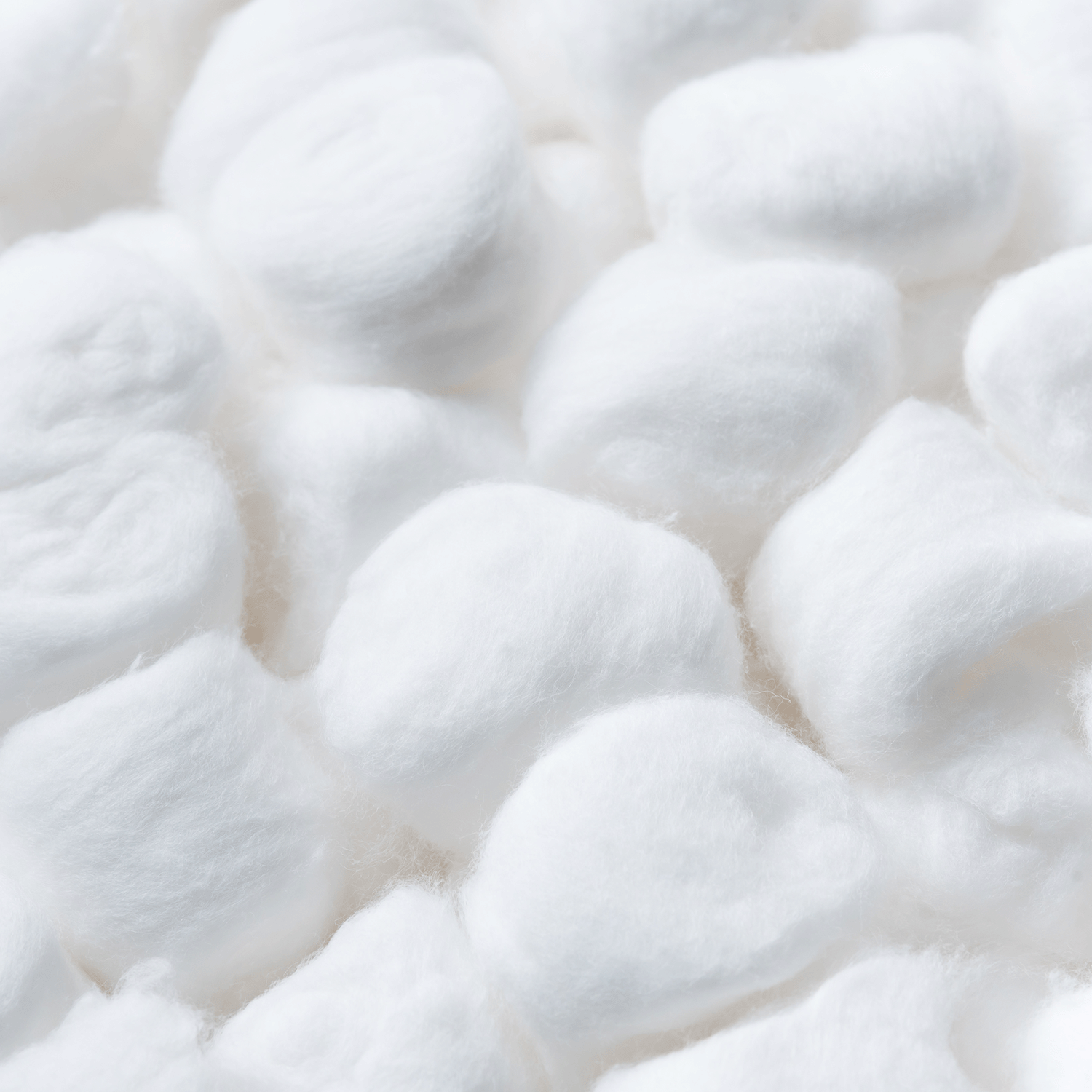 Close-up of several white cotton balls, their soft texture reminiscent of Tuscany Candle® SEASONAL’s Wildflower Breeze: Dandelion & Hibiscus Scented Spring Candle (14 oz).