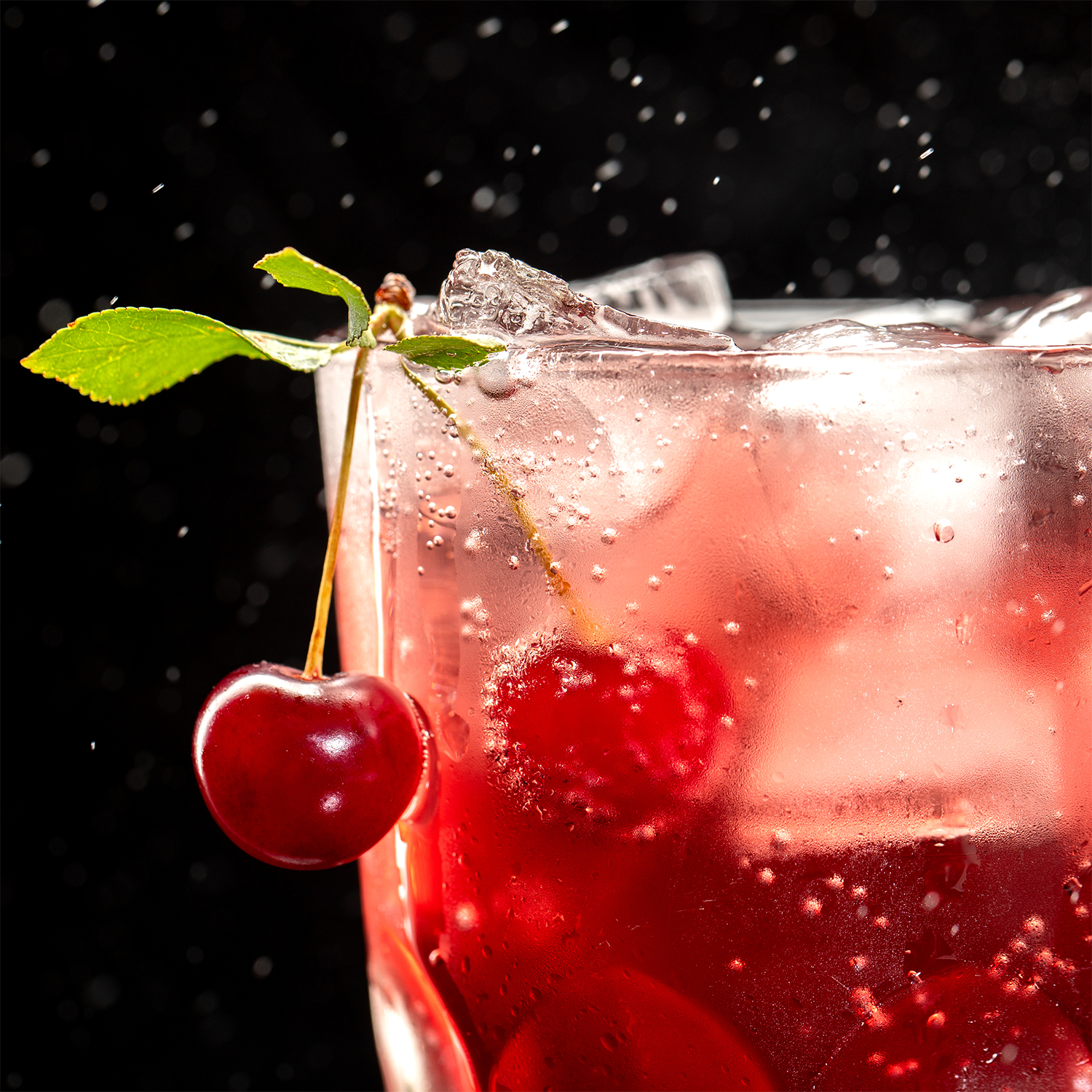A close-up of Tuscany Candle® SEASONAL’s Black Cherry & Plum: Sparkling Seltzer Scented Summer Candle (13 oz) evokes a refreshing red drink with cherry and leaf garnish, set against a dark, misty background—perfect for summer.