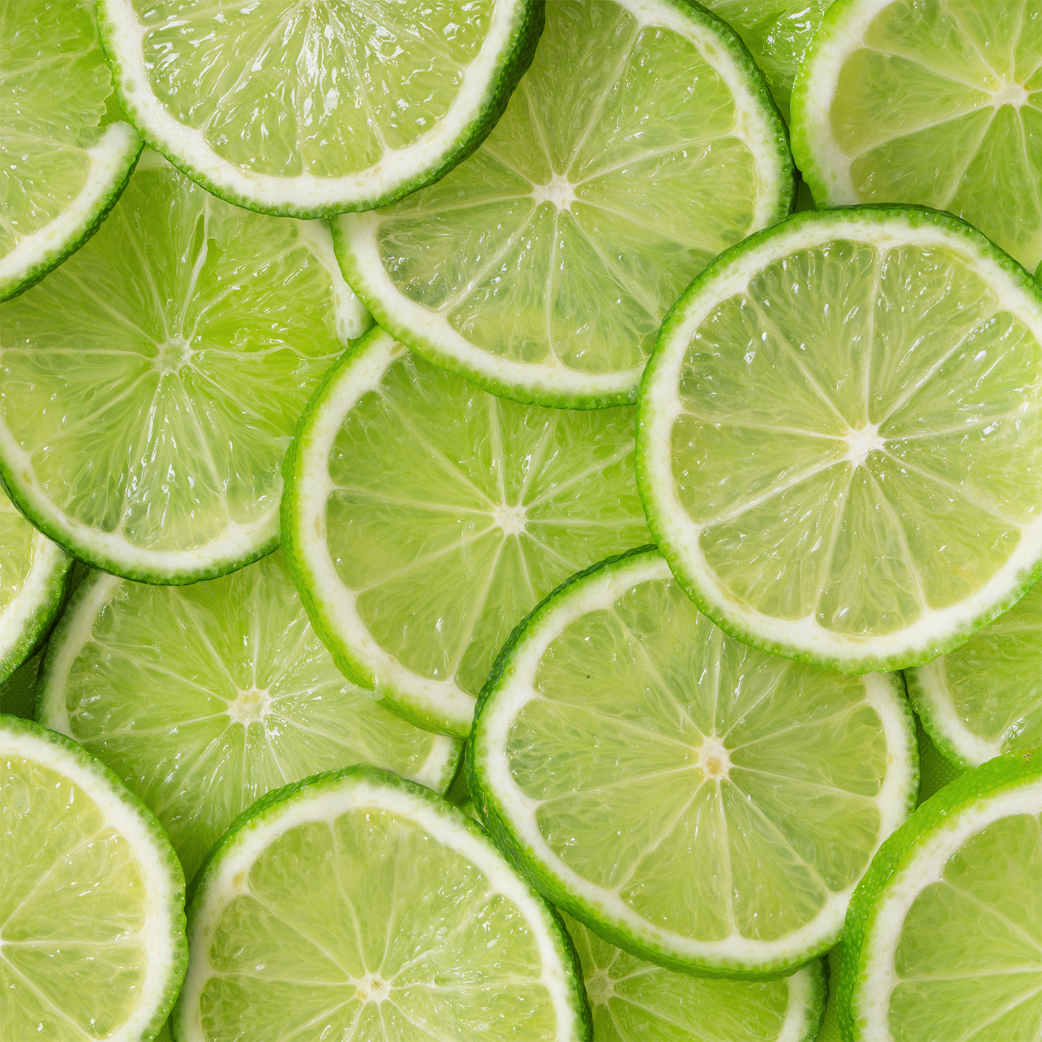 Close-up of overlapping sliced lime pieces, highlighting green rinds and juicy centers—evoking the zesty freshness of Tuscany Candle® SEASONAL Lemon Limeade: Sparkling Seltzer Scented Summer Candle (13 oz).