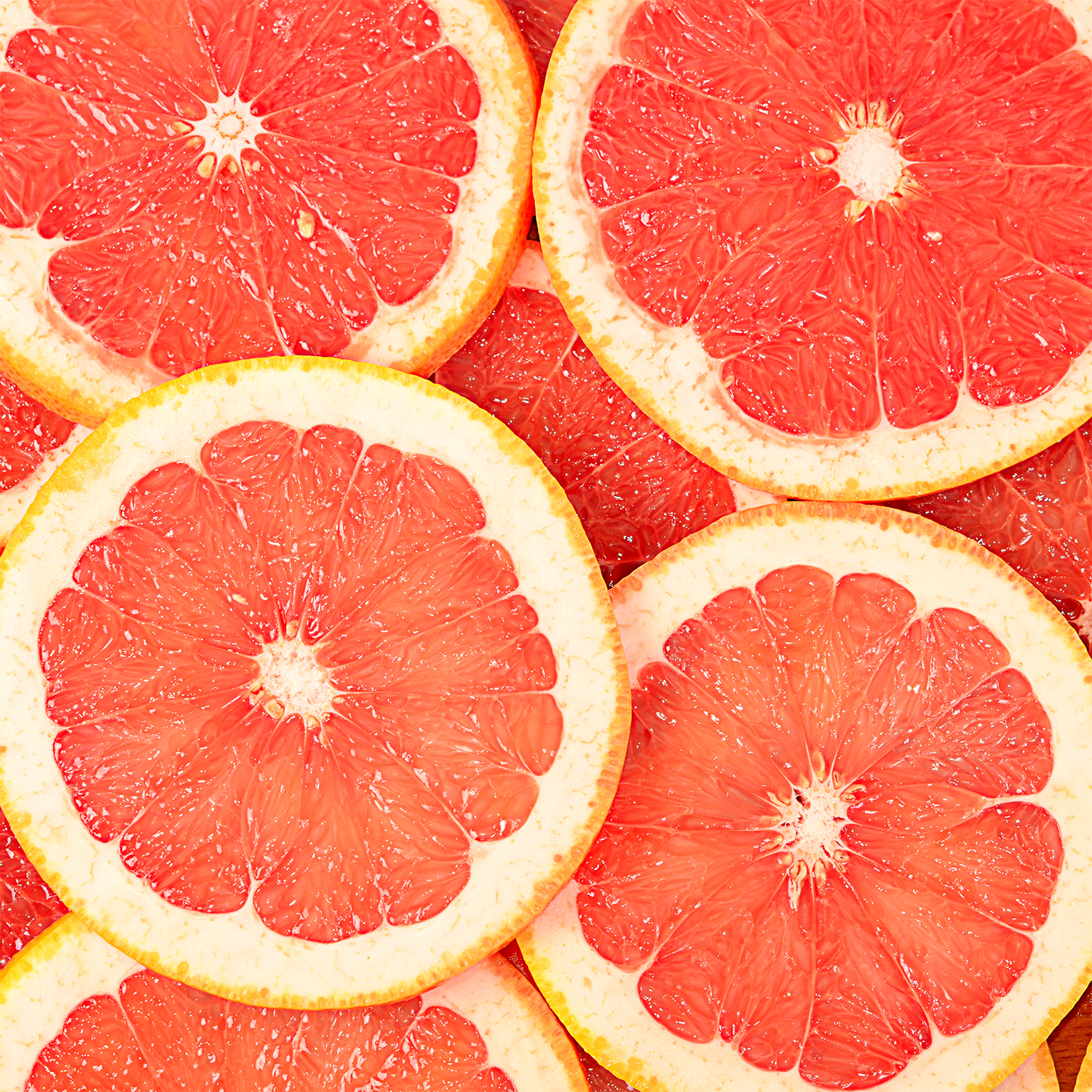 Close-up of juicy pink grapefruit slices with pale yellow rinds—like the refreshing scent of Tuscany Candle® SEASONAL’s Cactus Cooler: Sparkling Seltzer Scented Summer Candle (13 oz).