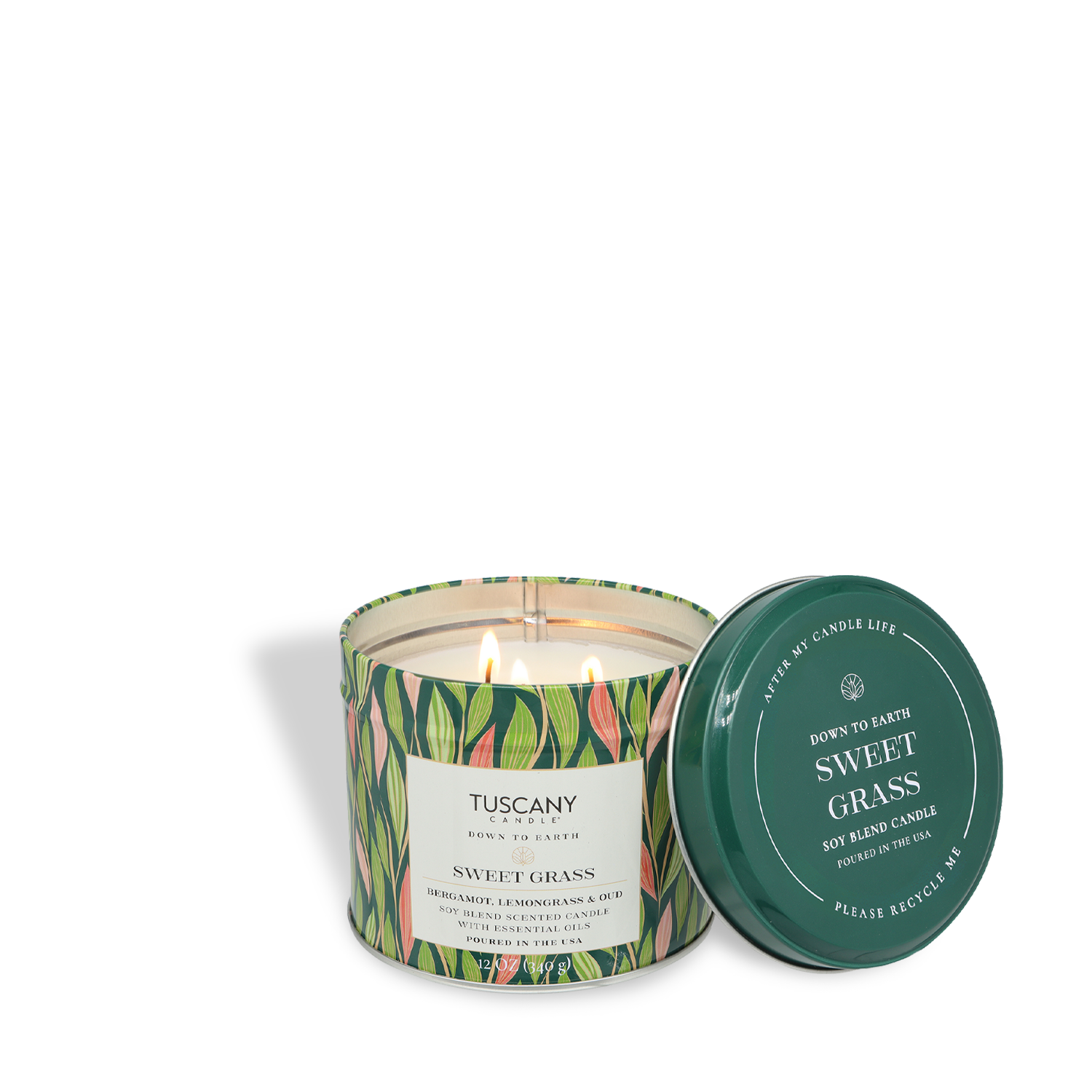 A lit Tuscany Candle® SEASONAL Sweet Grass: Bergamot & Oud Scented Spring Tin Candle (12 oz) from the Down to Earth Collection sits in a green leafy-patterned container—an inviting botanical candle perfect for spring.