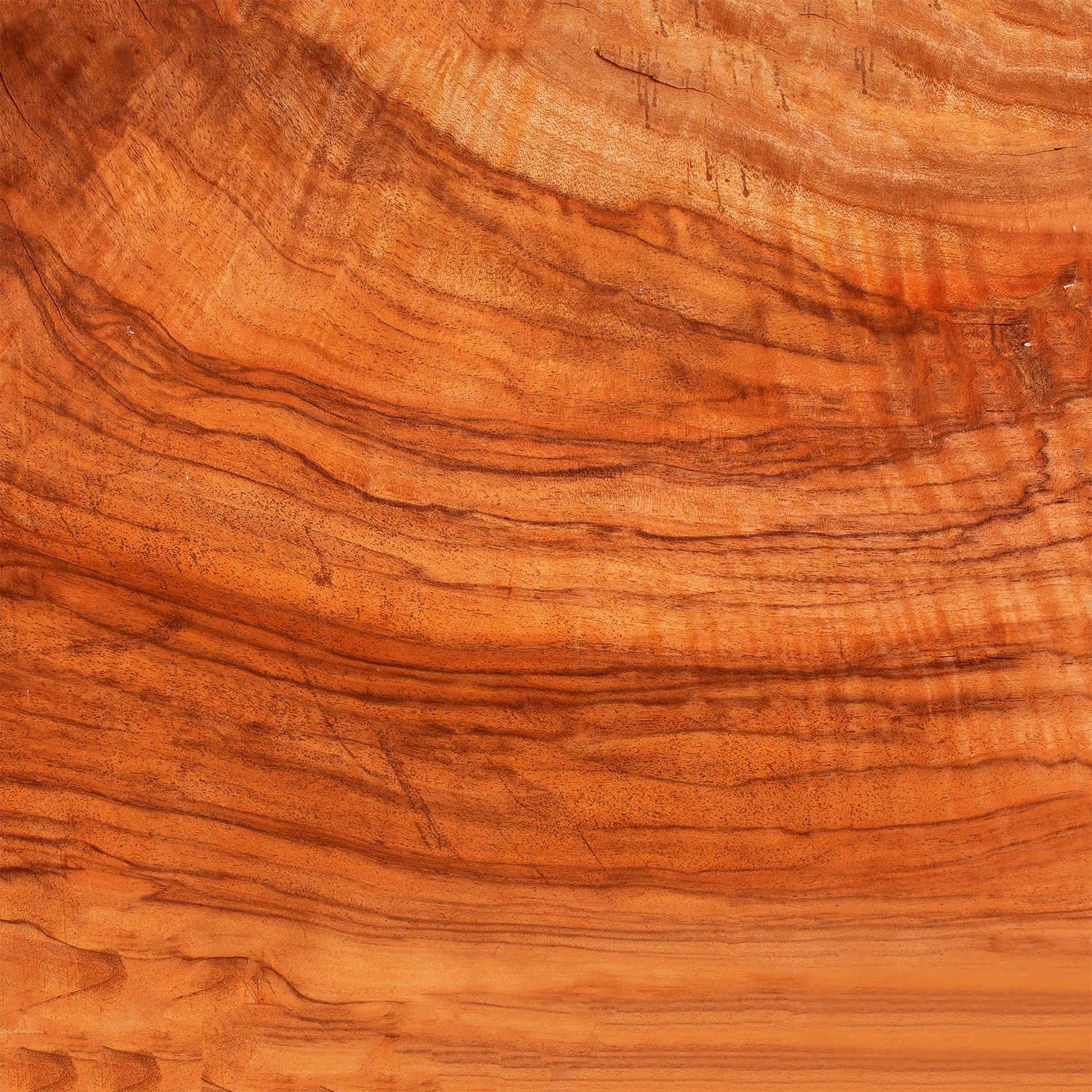Close-up of polished wood surface reflects the rich reddish-brown tones and grain patterns inspired by Tuscany Candle® SEASONAL's Independence: Mahogany & Suede Scented Summer Candle (14 oz).
