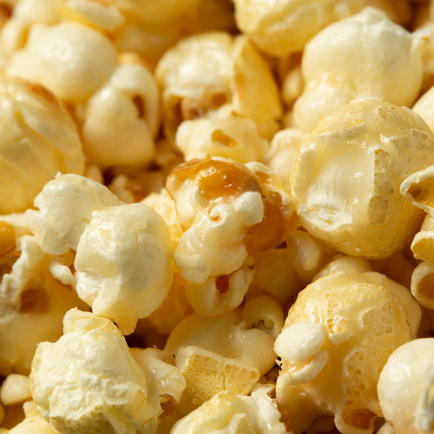 Close-up of several pieces of Monster Bites: Caramel Kettlecorn Scented Halloween Candle Wax Melt (2.5 oz) by Tuscany Candle® SEASONAL, showing the texture and details that resemble popped, buttery popcorn kernels.