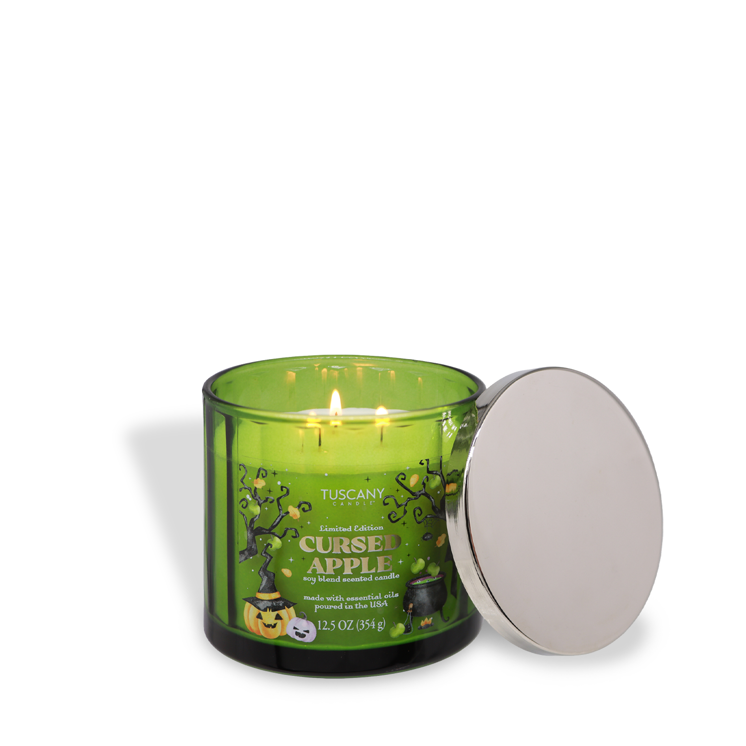 A green glass candle labeled “Cursed Apple: Nutty Caramel Apple Scented Halloween Candle (12.5 oz)” by Tuscany Candle® SEASONAL glows with three flames, its silver lid set aside.