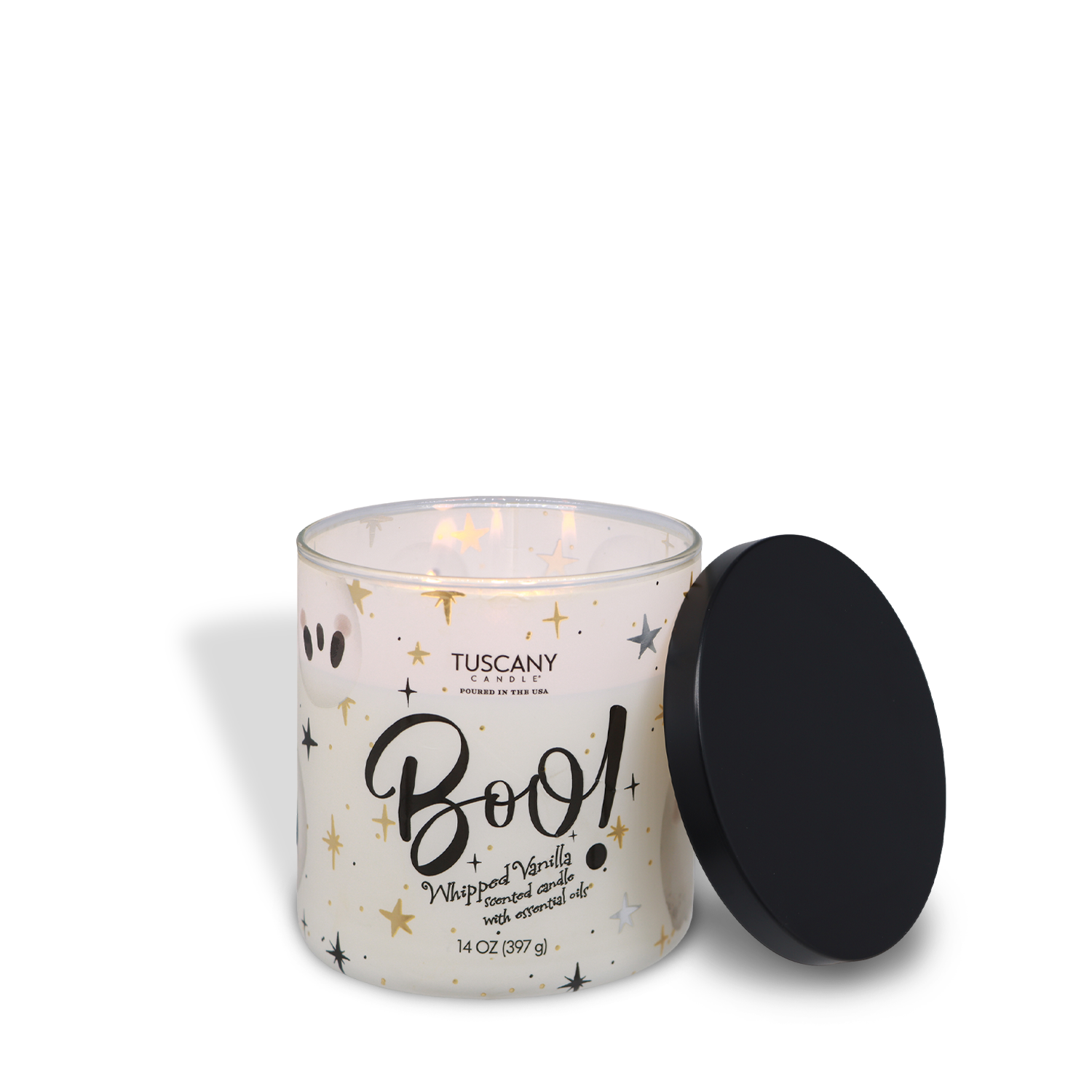 A lit Tuscany Candle® SEASONAL “Boo: Whipped Vanilla Scented Halloween Candle” (14 oz) in a decorated glass jar sits with its black lid beside it, featuring a festive design of stars and ghost faces for Halloween.