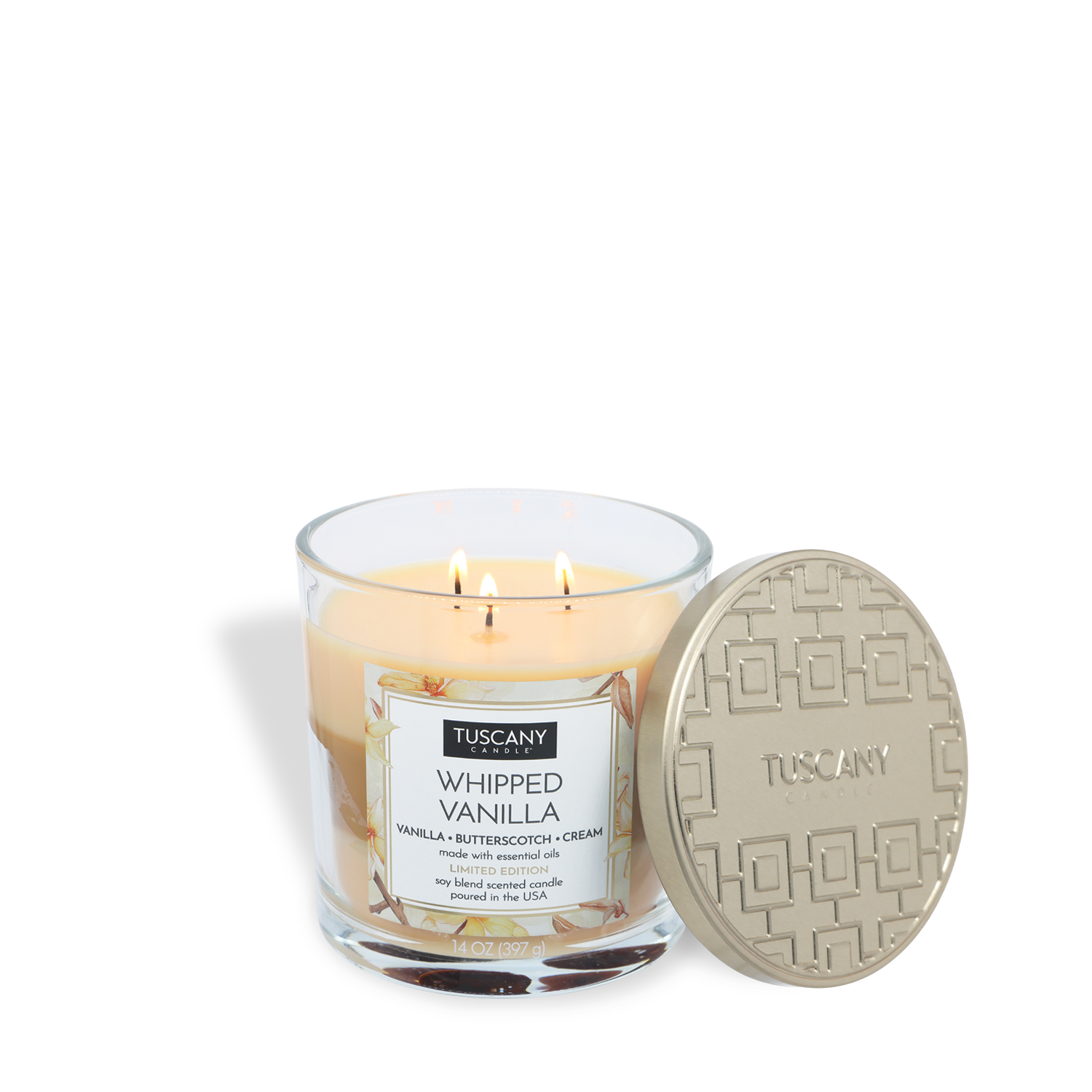 A Tuscany Candle® SEASONAL Whipped Vanilla: Butterscotch & Cream Scented Fall Candle (14 oz) with three wicks is burning in a clear glass jar, and the beige lid sits beside it.