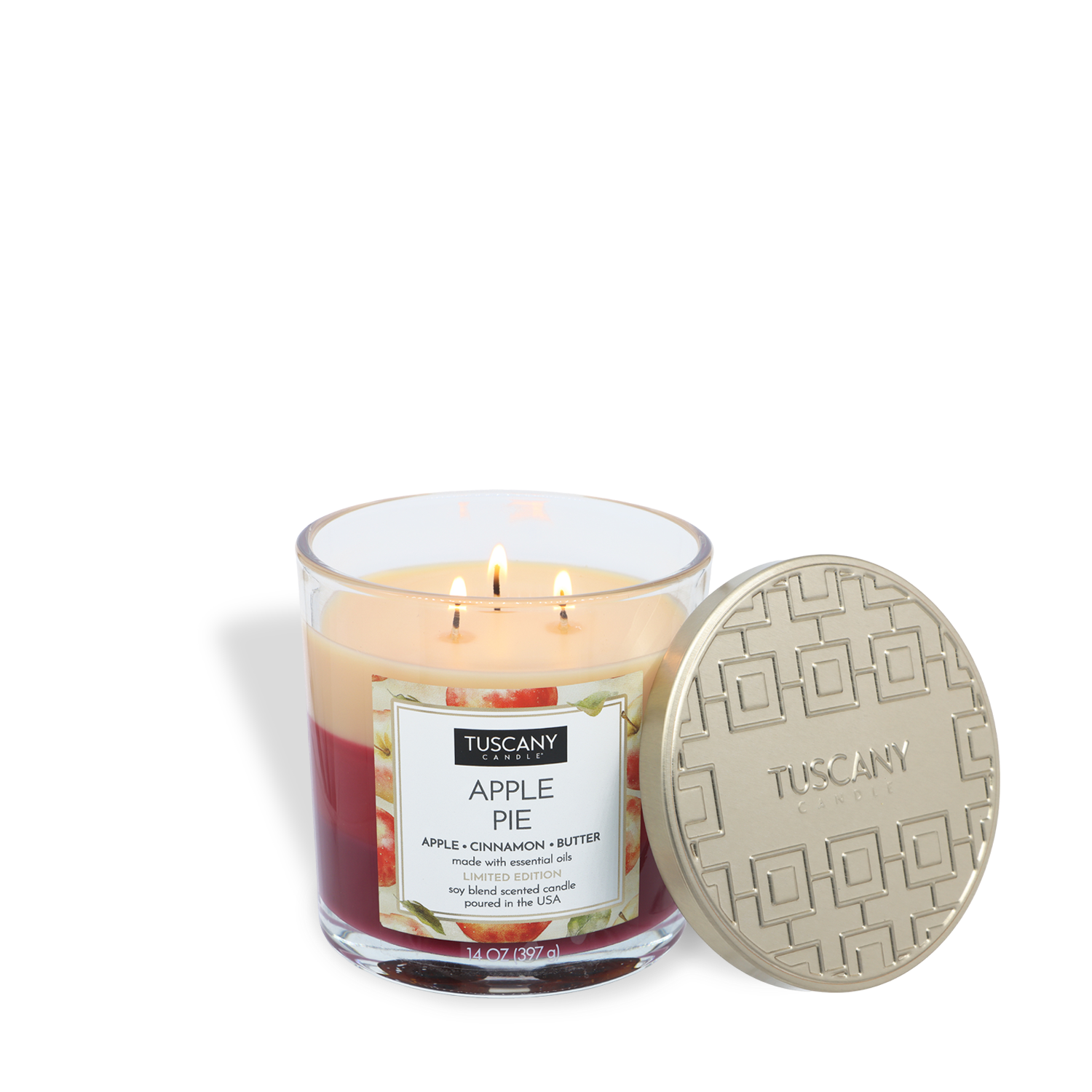 A Tuscany Candle® SEASONAL "Apple Pie: Cinnamon & Butter Scented" 14 oz fall candle with three lit wicks sits in a glass jar, its decorative gold lid placed to the side.
