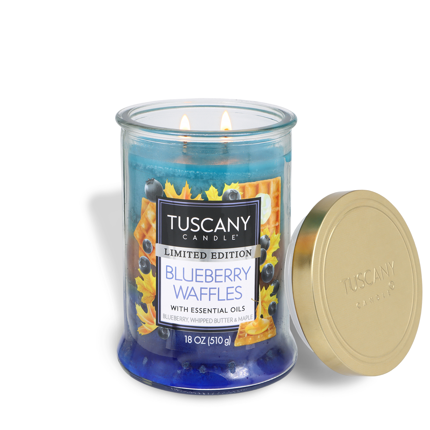An 18 oz blue glass jar candle from Tuscany Candle® SEASONAL, labeled "Blueberry Waffles: Whipped Butter & Maple," with a gold lid, two lit wicks, and a label featuring waffles and blueberries.