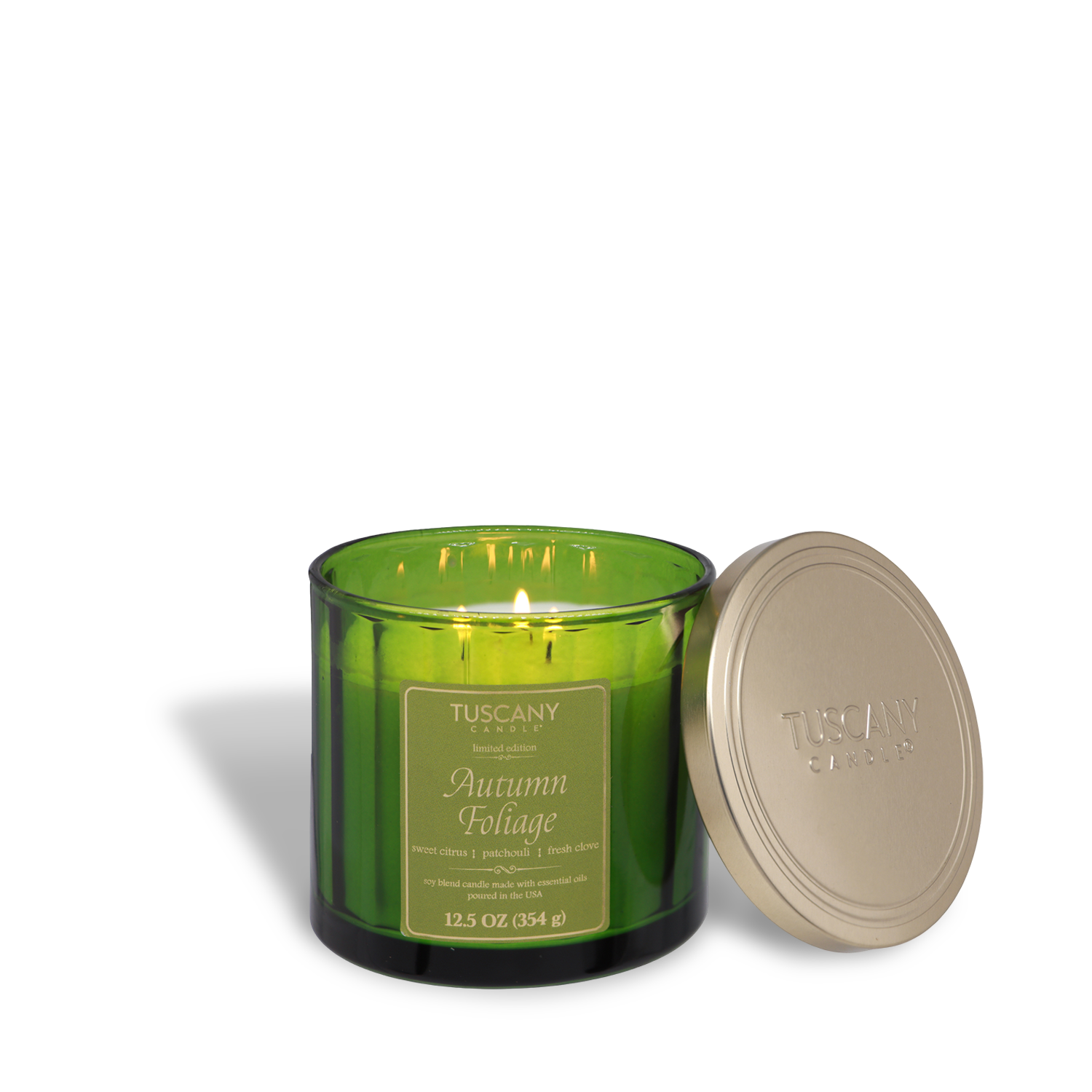 A green glass Tuscany Candle® SEASONAL "Autumn Foliage: Citrus & Patchouli" fall candle (12.5 oz) with three lit wicks and a gold lid beside it, made with soy blend wax.