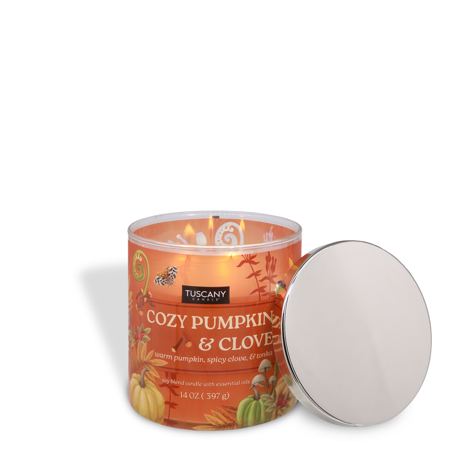 A lit Tuscany Candle® SEASONAL "Cozy Pumpkin & Clove: Warm Tonka Scented Fall Candle" (14 oz) with an autumn design sits beside its removed silver lid.