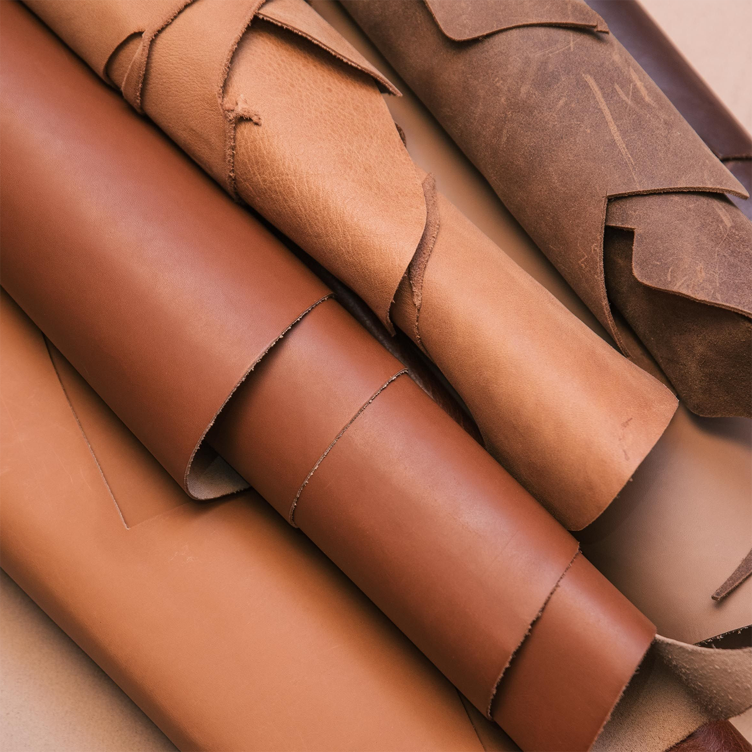 Multiple rolls of brown leather, showcasing a variety of shades and textures, are arranged closely together on a flat surface—reminiscent of the warm, inviting aroma captured in Tuscany Candle® SEASONAL’s Backwoods Bound: Leather & Tobacco Scented Fall Wooden Wick Candle (14.5 oz).