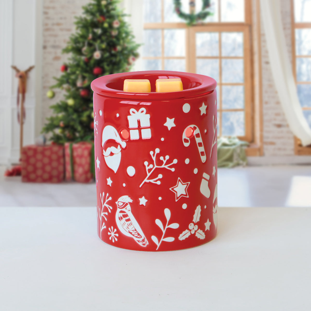 Red electric wax warmer featuring a white holiday pattern of Santa, gifts, and candy canes, melting two yellow cubes of Yuletide Vanilla: Smooth Rum & Clove Scented Holiday Wax Melt.