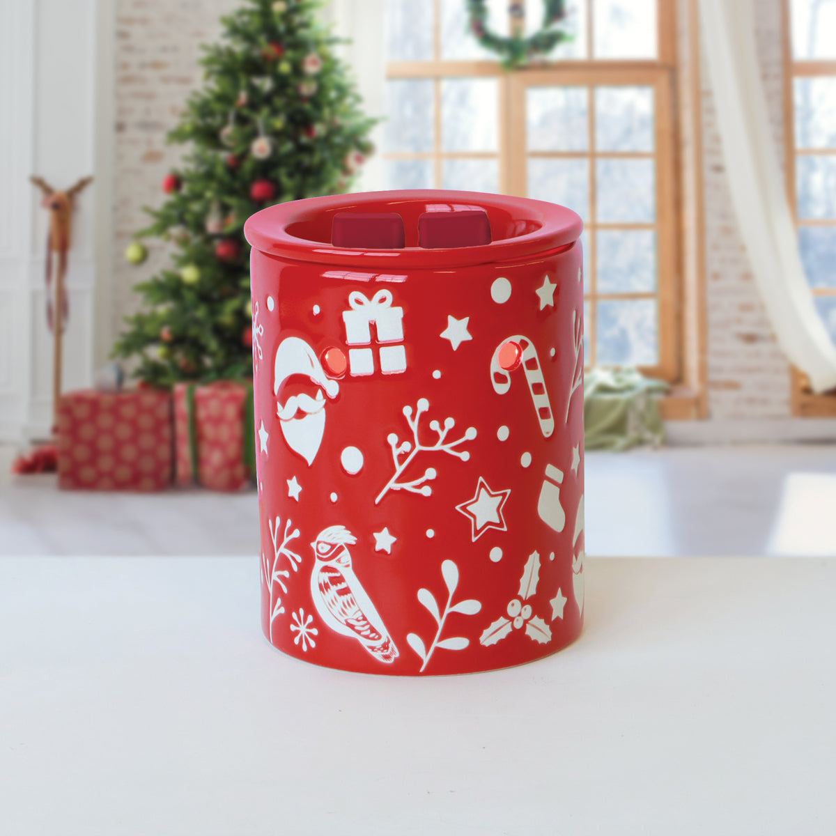Red electric wax warmer featuring white holiday-themed illustrations including Santa, gift boxes, and candy canes for Spiced Pinecones: Cinnamon & Pine Scented Holiday Wax Melt (2.5 oz) by Tuscany Candle® SEASONAL.