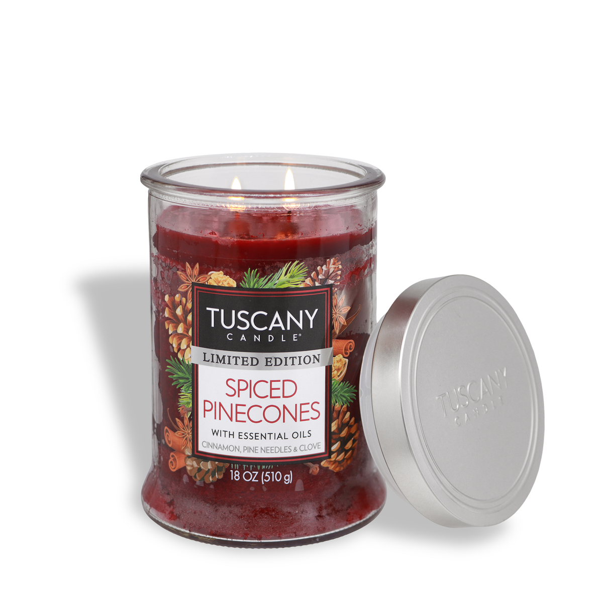 A two-wick red Tuscany Candle® SEASONAL Spiced Pinecones: Cinnamon & Pine Scented Holiday Candle (18 oz) in a glass jar with a silver lid, featuring an illustration of pinecones and evergreen branches.