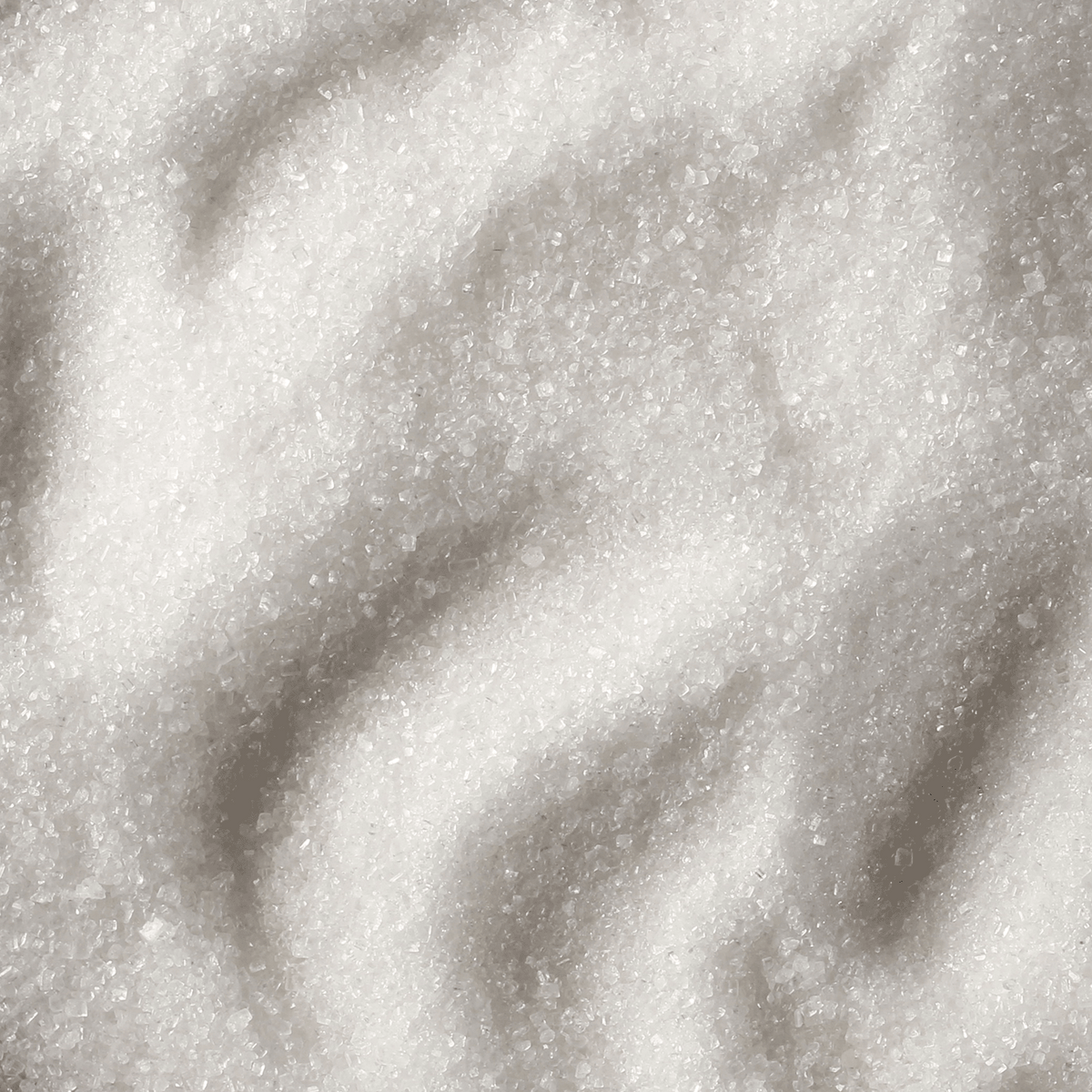 A close-up view of white, granulated sugar crystals on a Peppermint Fluff: Sugared Vanilla & Peppermint Scented Holiday Candle (18 oz) by Tuscany Candle® SEASONAL.