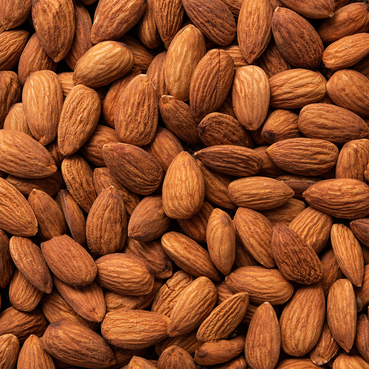 A close-up, full-frame view of raw almonds, the inspiration for a Mrs. Claus’s Cookies: Almond & Cardamom Scented Holiday Candle (14 oz) by Tuscany Candle® SEASONAL.