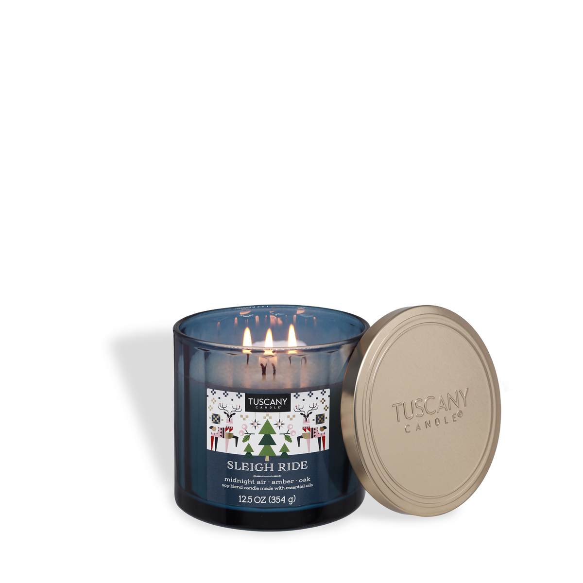 Tuscany Candle® SEASONAL Sleigh Ride: Golden Amber & Oak Scented Holiday Candle (12.5 oz) in a blue glass jar with a lit three-wick flame, a gold lid to the side, and a holiday-themed label.