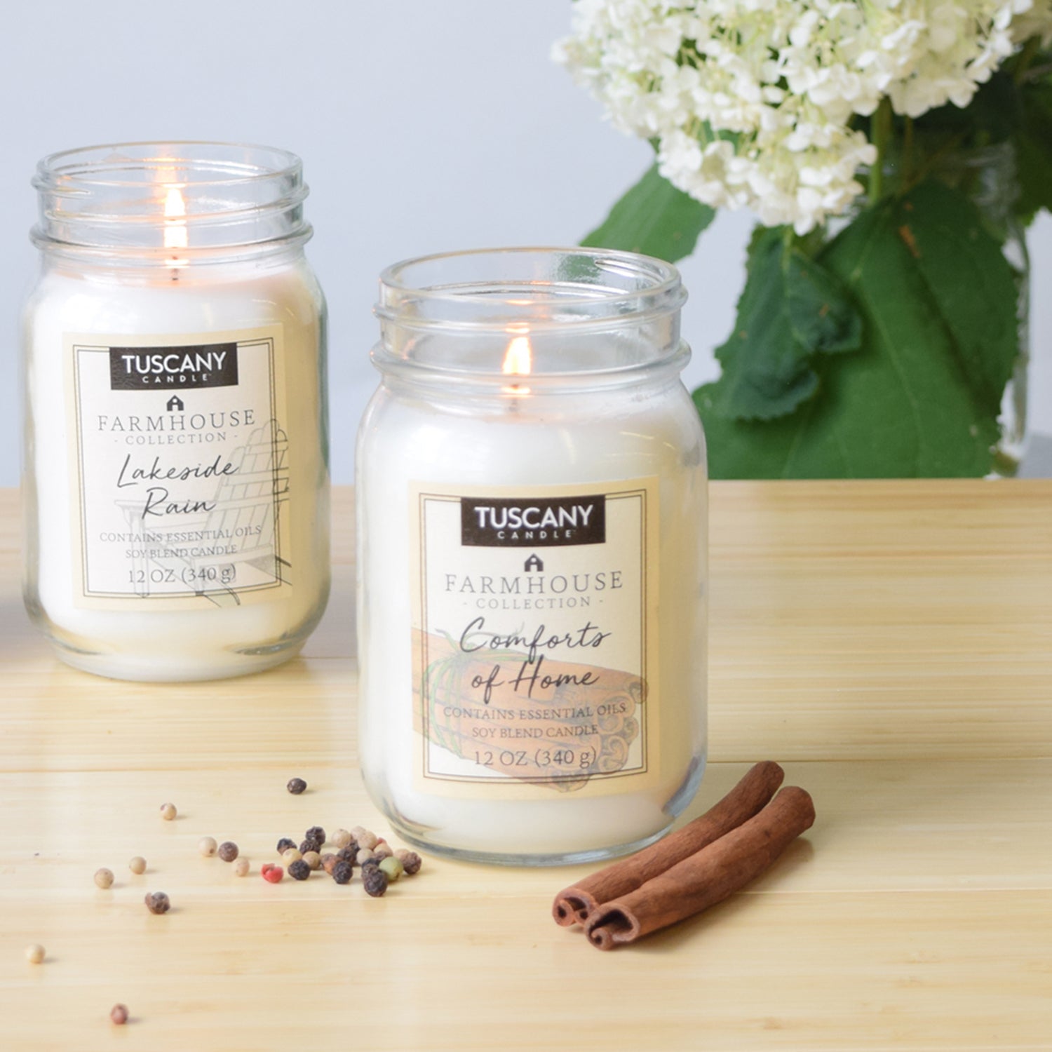 A Tuscany Candle farmhouse collection of scented candles, including one Lakeside Rain Scented Jar Candle (12 oz) – Farmhouse Collection, beautifully displayed on a wooden table.