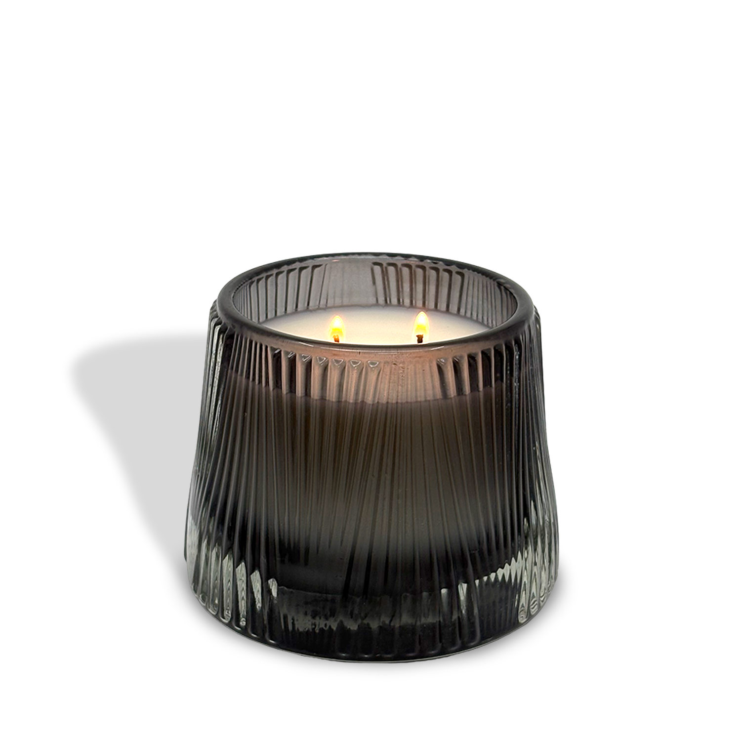 The est.1951 Bergamot & Musk (9oz) candle, featuring two lit wicks and vegan wax in a black ribbed glass holder, casts a shadow on a white background.