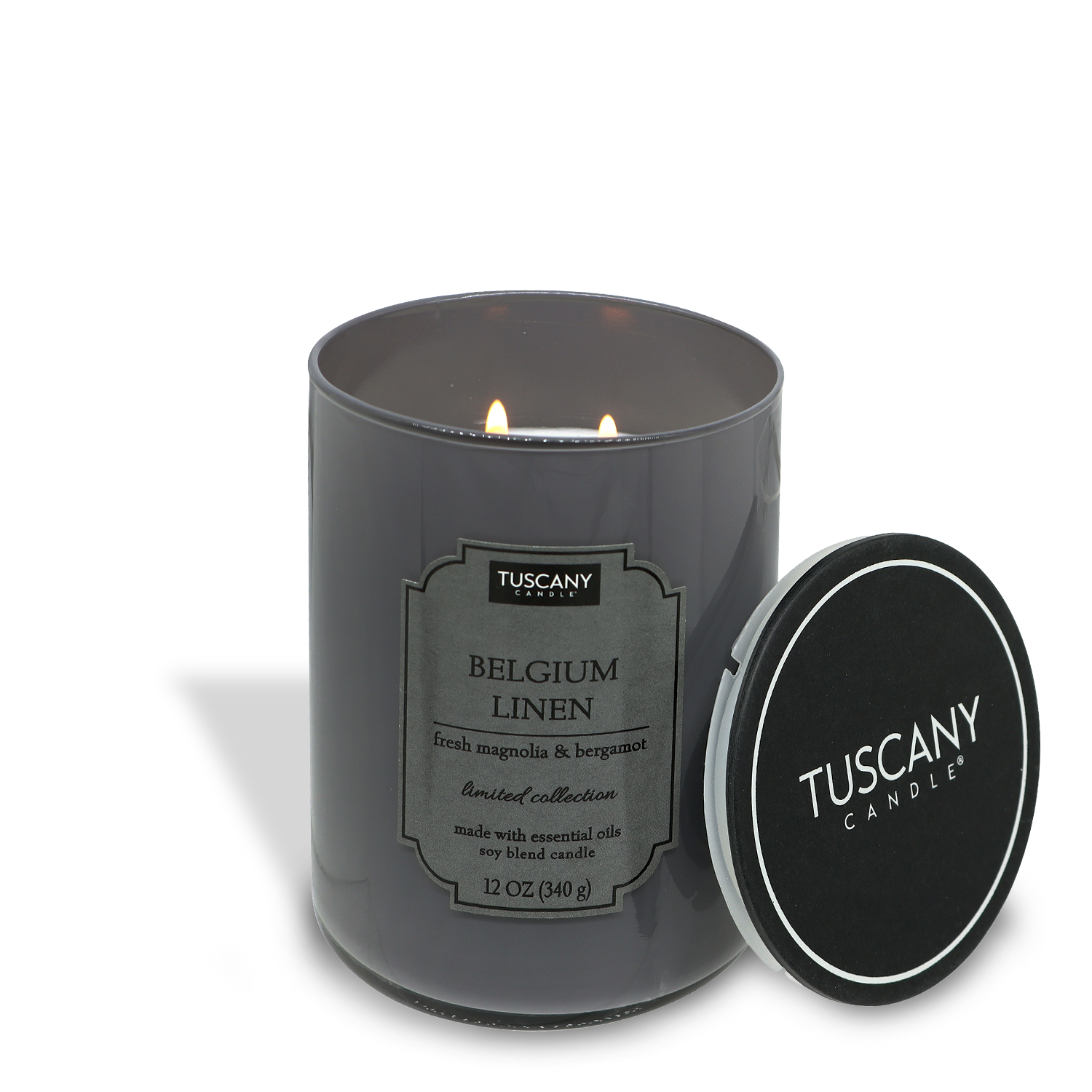 A lit Tuscany Candle® EVD Belgium Linen candle from the Colorsplash collection in a dark glass jar with the lid off to the side against a white background.