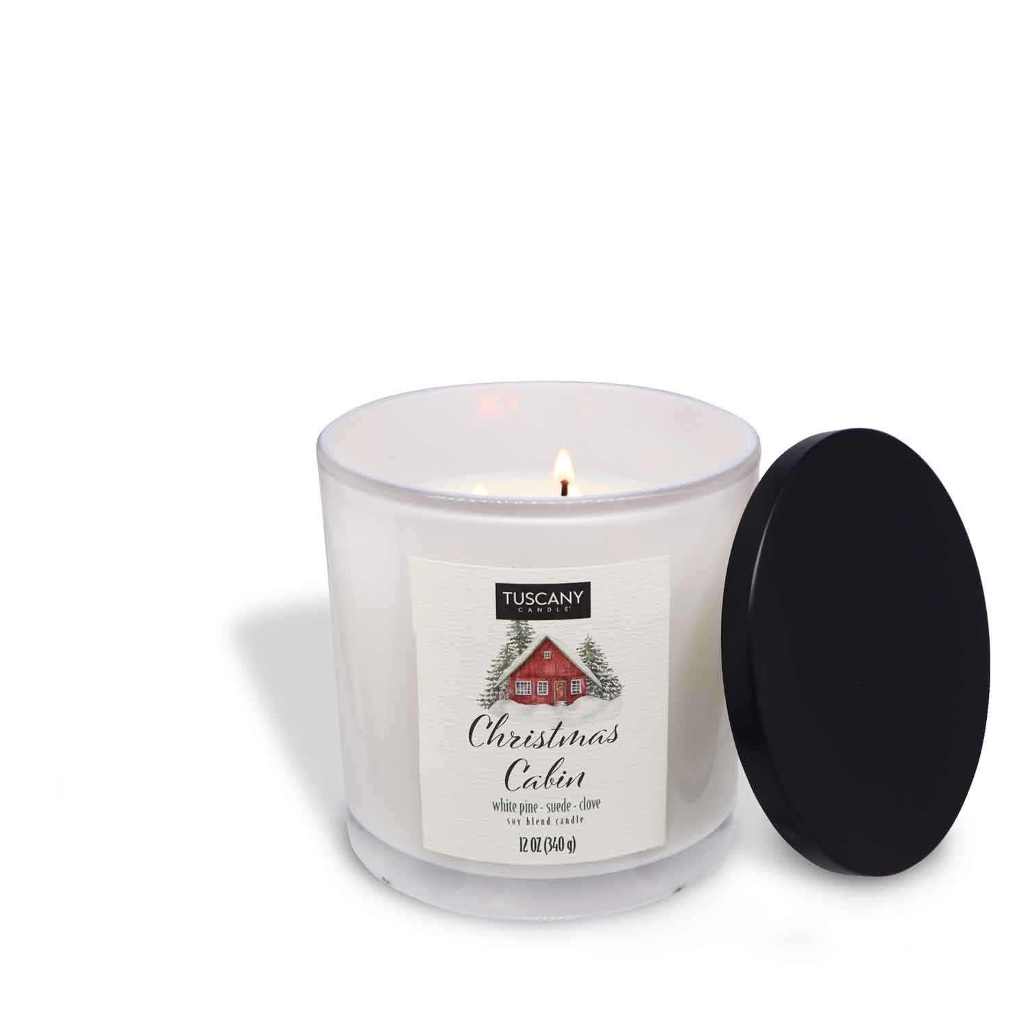 12oz Christmas Cabin scented candle in a glossy white glass jar with a black lid, filled with white wax, releasing scents of white pine, rich suede, and dark cloves from the Winter candle collection