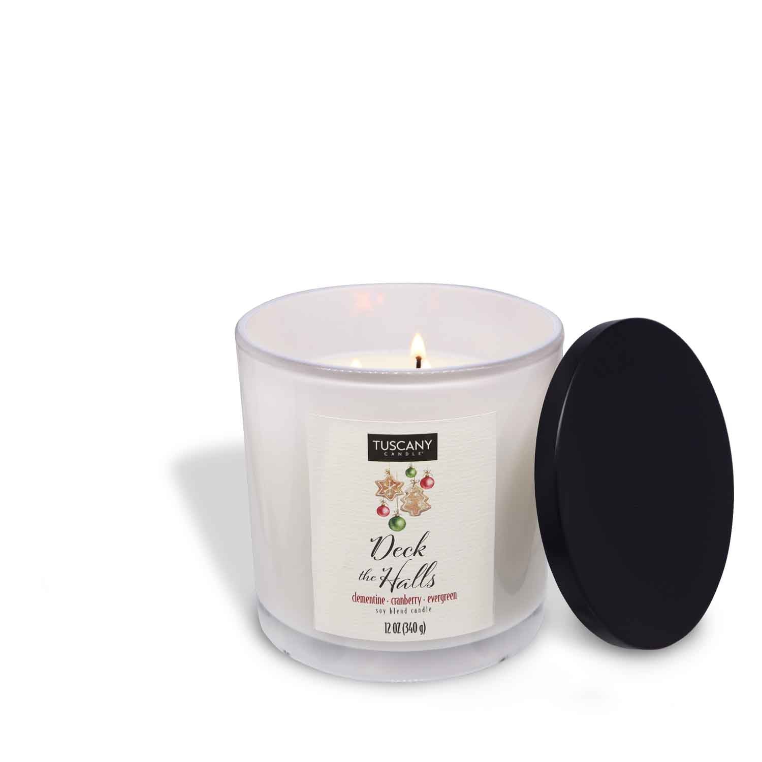 2oz Deck The Halls scented candle in a glossy white glass jar with a gold lid, emanating the festive blend of clementine, cranberry, and evergreen from the Winter candle collection.