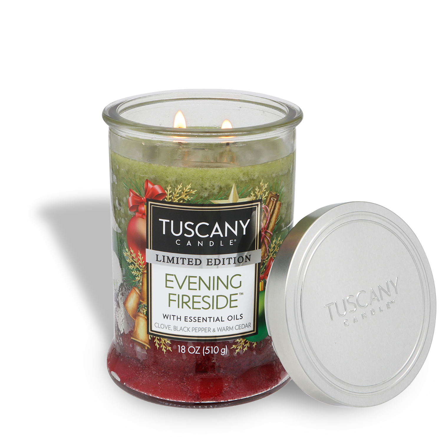 An 18 oz Tuscany Candle® SEASONAL Evening Fireside™ holiday candle with a spicy & warm cedar scent, festive design, two lit wicks, and the lid set aside.