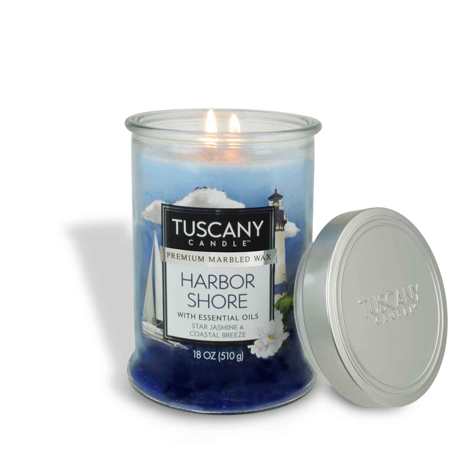 A burning Tuscany Candle® EVD Harbor Shore Long-Lasting Scented Jar Candle (18 oz), featuring essential oils of star jasmine and coastal breeze, with the lid placed beside the jar.